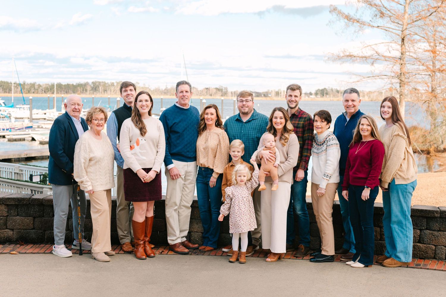 Large family group photo by the water wearing coordinated cream and blue casual attire.