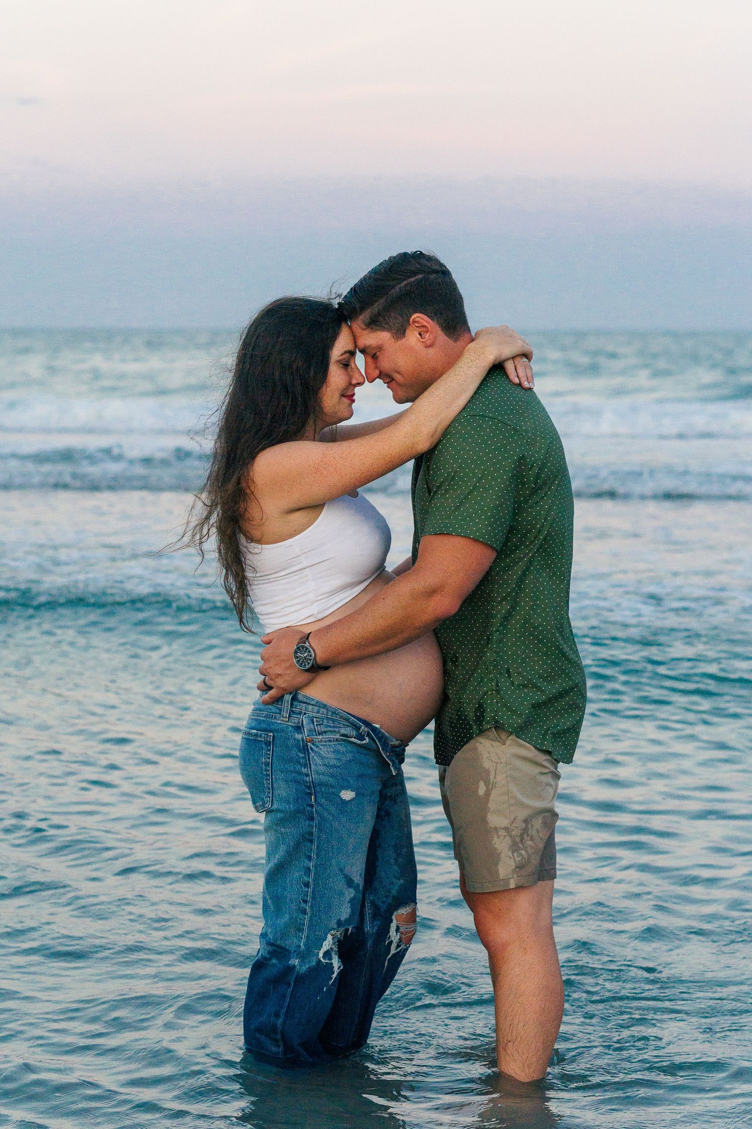 Intimate couple moment captured in crystal blue ocean waters during beach photoshoot.