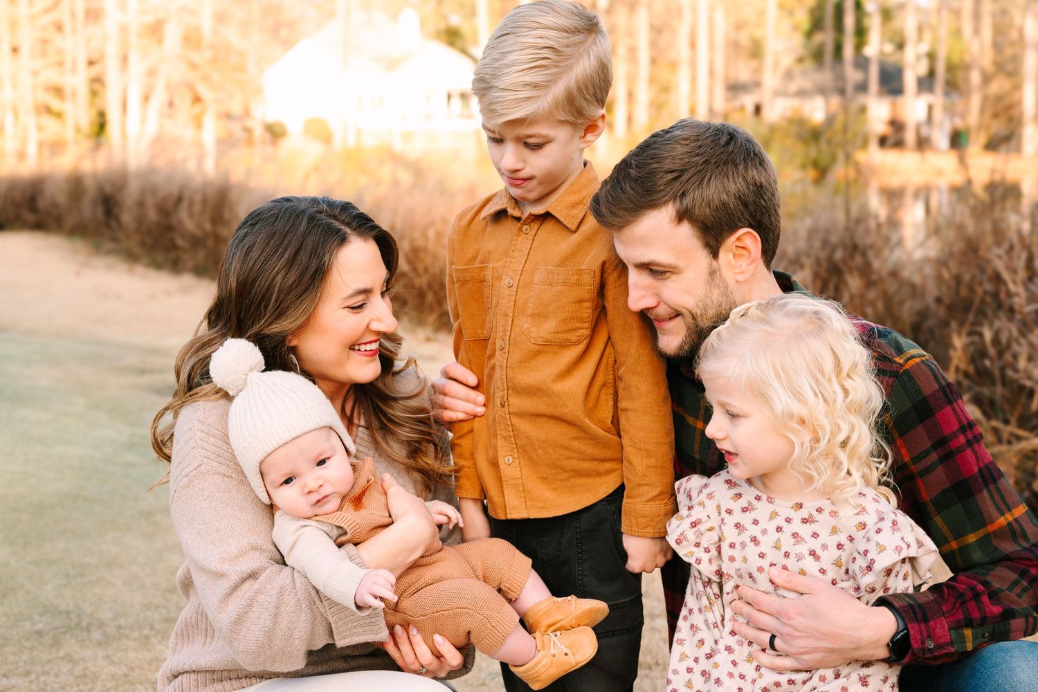 Family sitting together on ground outdoors during golden hour photo session.