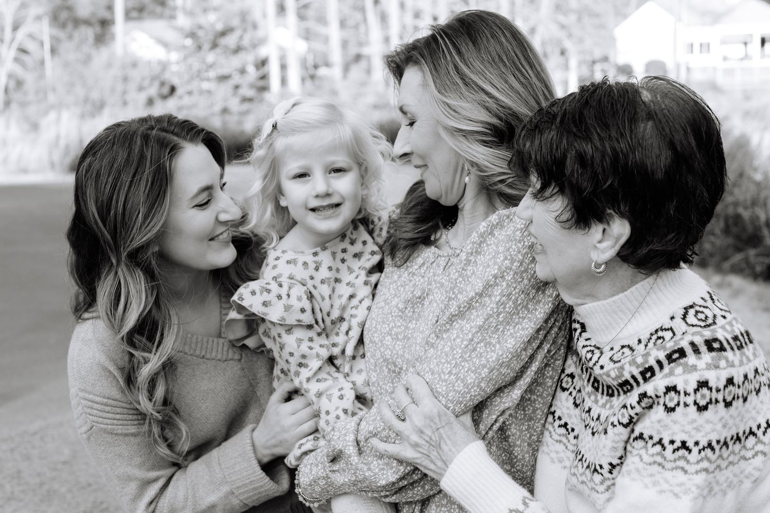 Multi-generational family moment captured in black and white with natural expressions and warm sweaters.