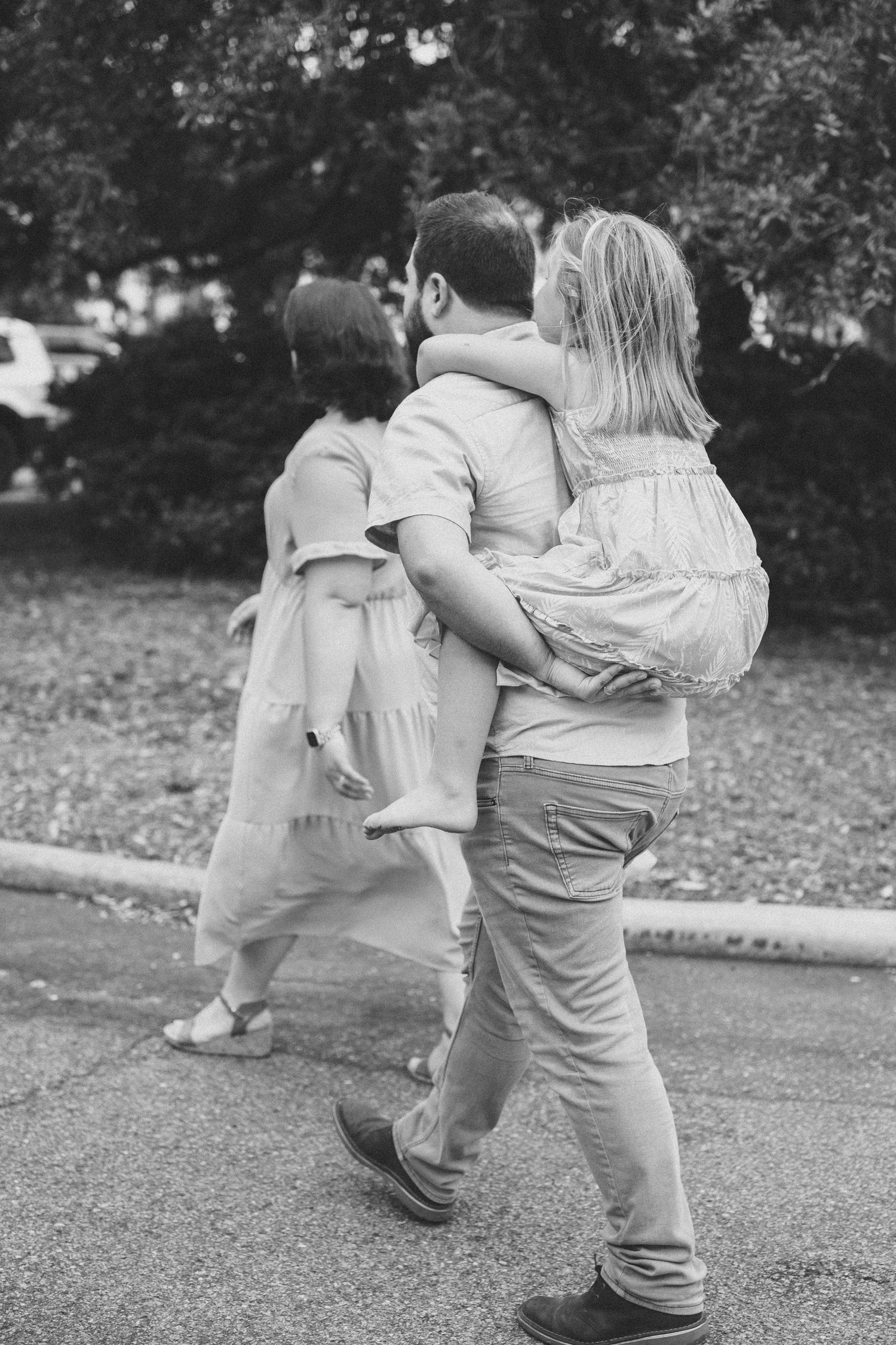 A black and white photograph of a family embracing on a garden pathway.
