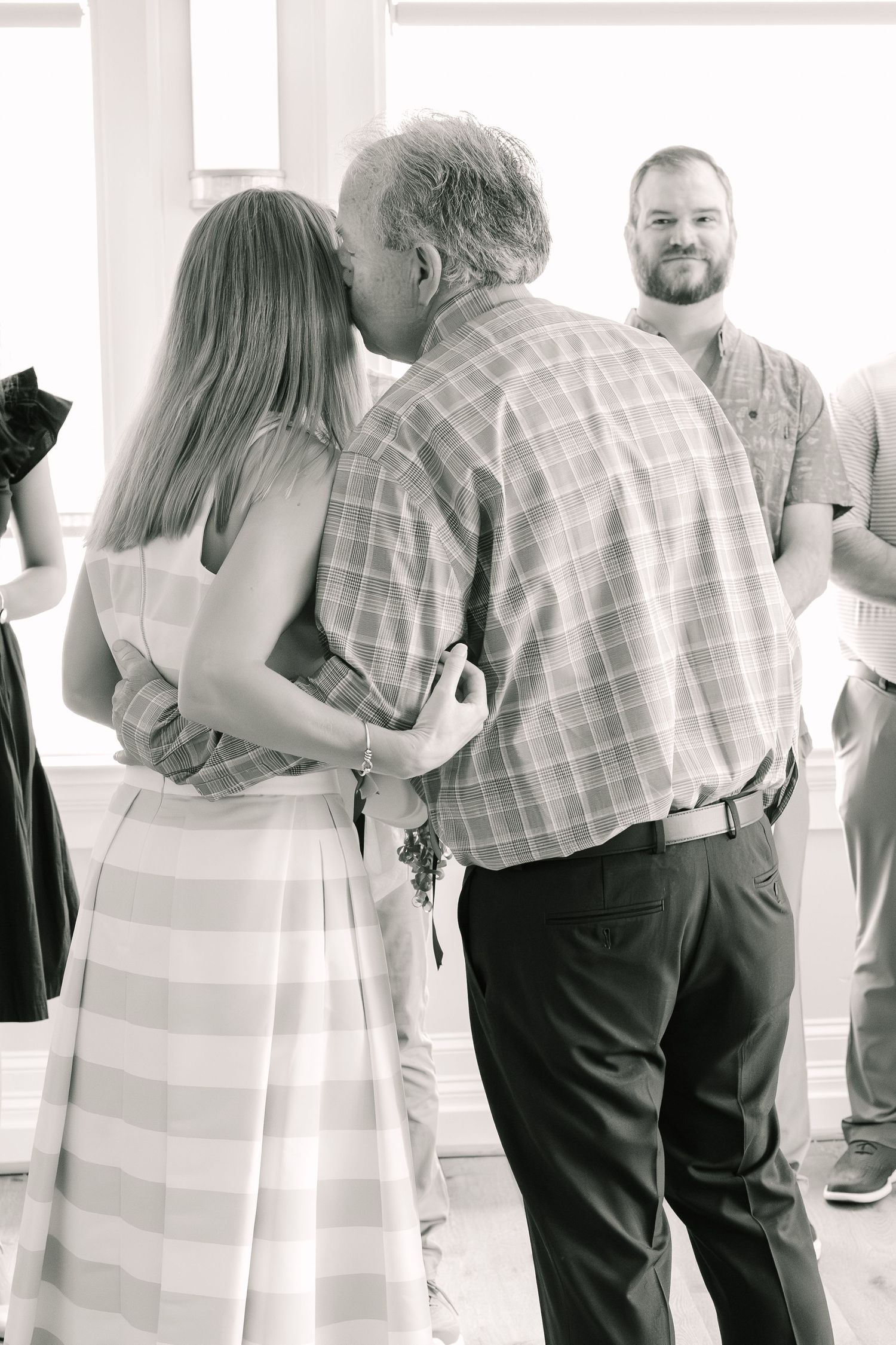 A black and white candid photo showing people gathering at what appears to be a social event or celebration.