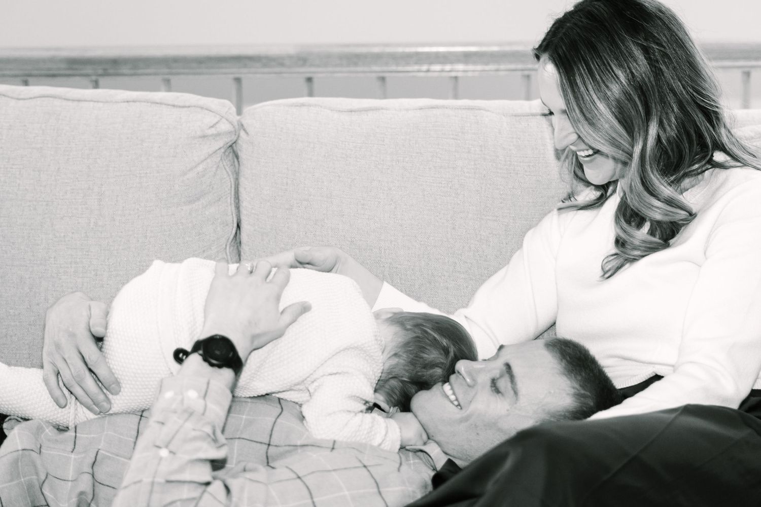 Black and white photo of family relaxing together on couch.
