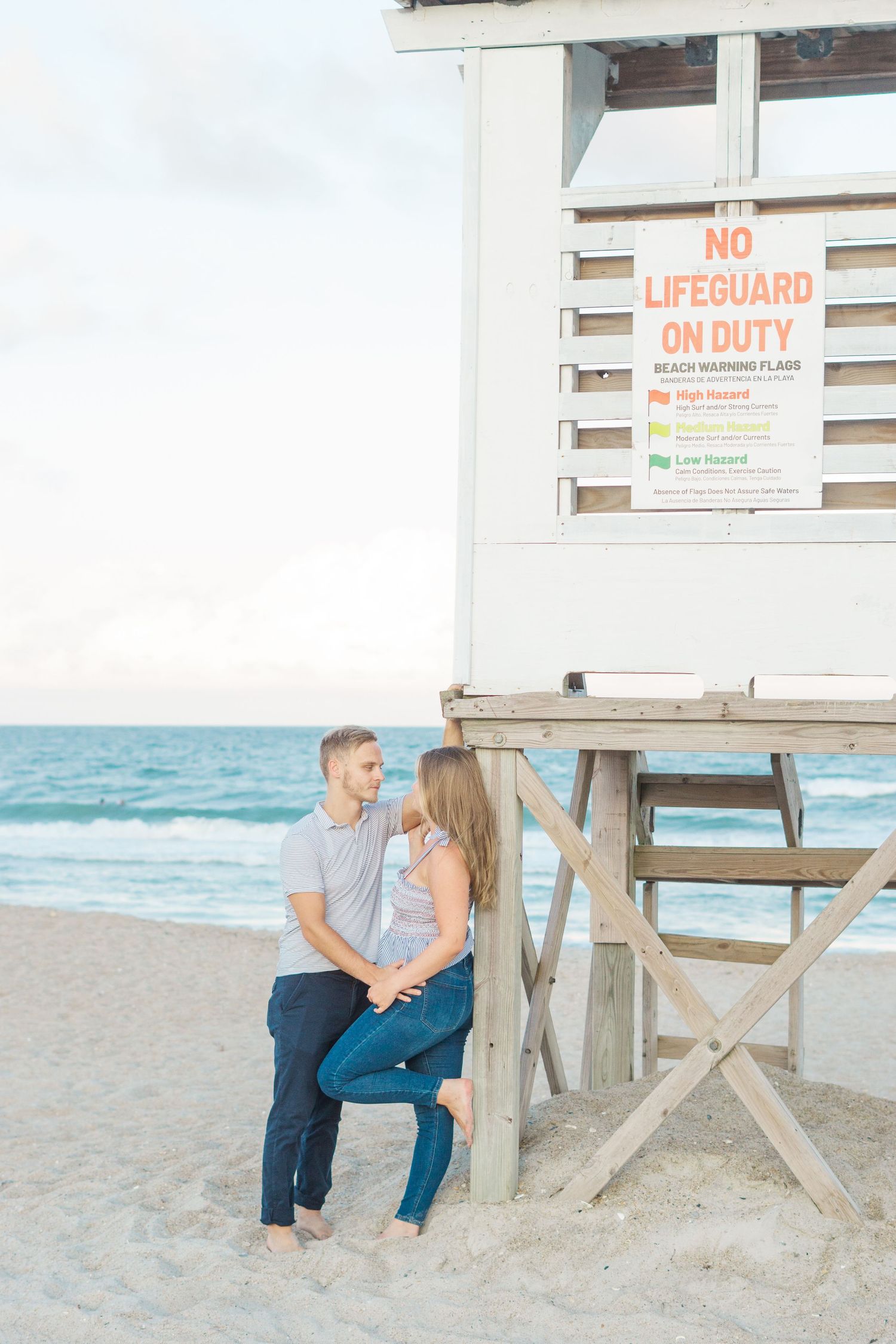 Romantic couple sitting by lifeguard tower on beach at sunset.