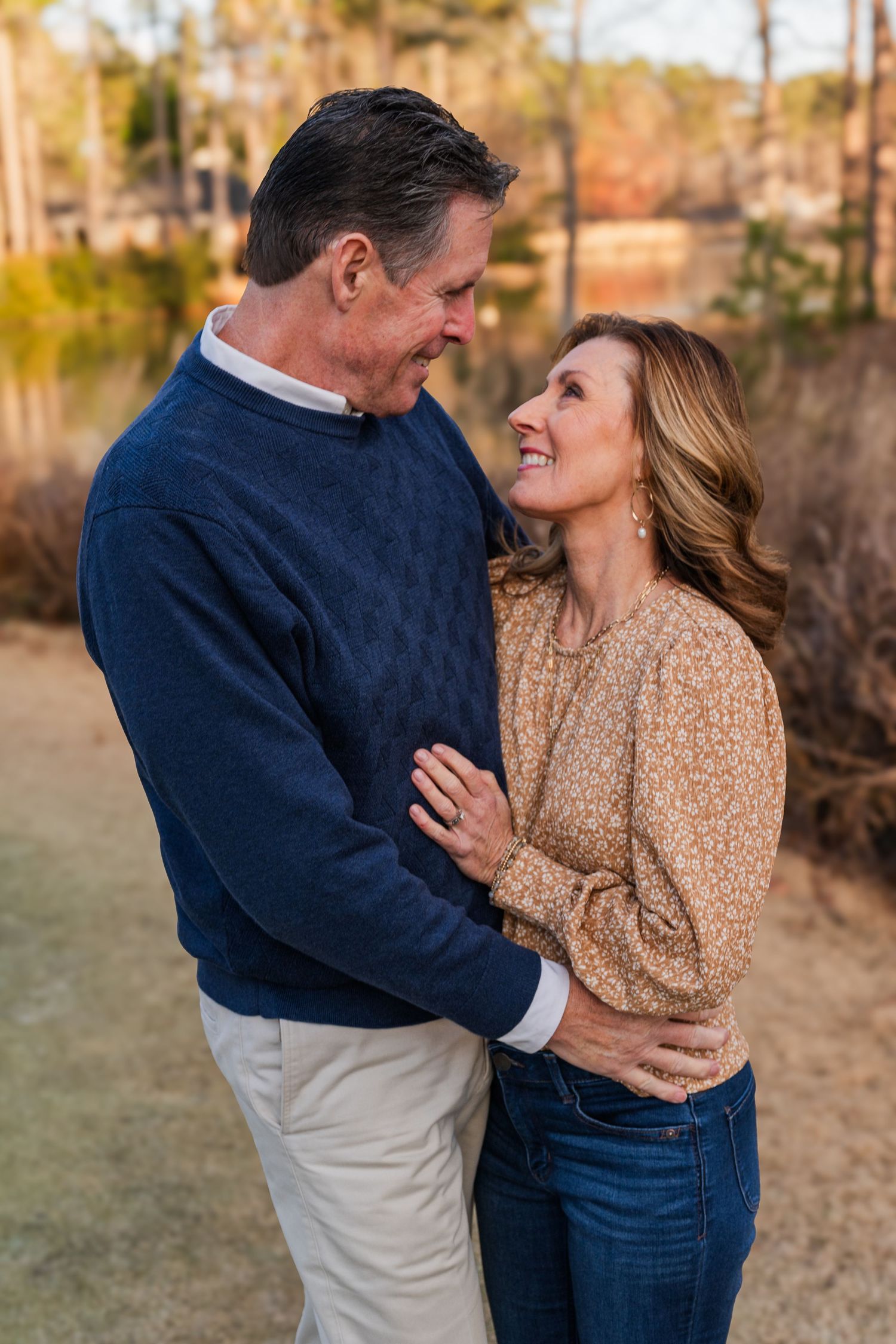 Two people share an intimate moment outdoors at sunset wearing casual sweaters.