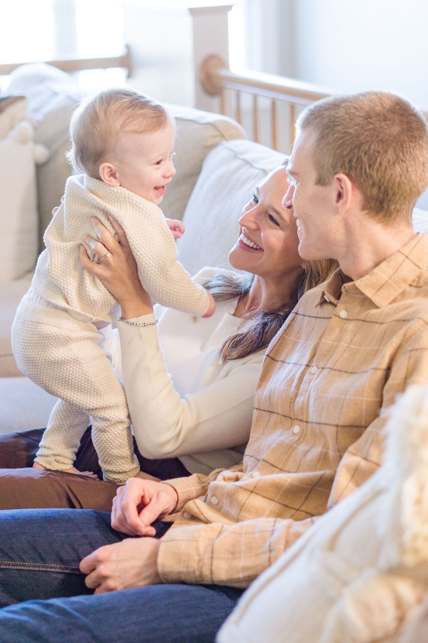 A family plays together on a cozy couch in a bright, sunlit room.