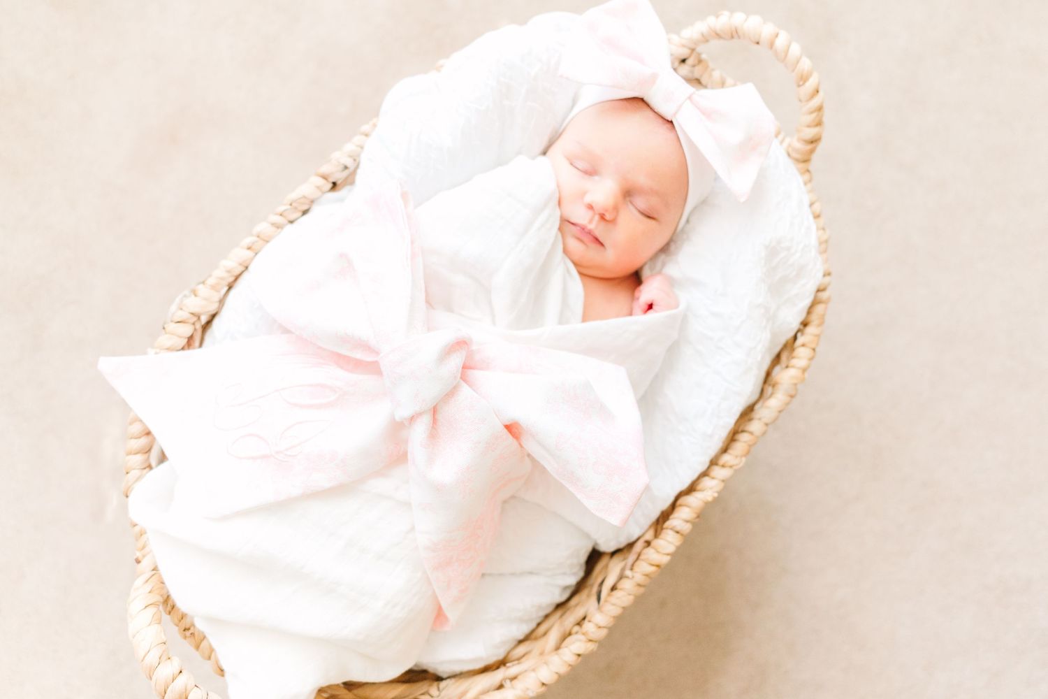 A black and white close-up portrait of a sleeping infant swaddled in soft fabric.