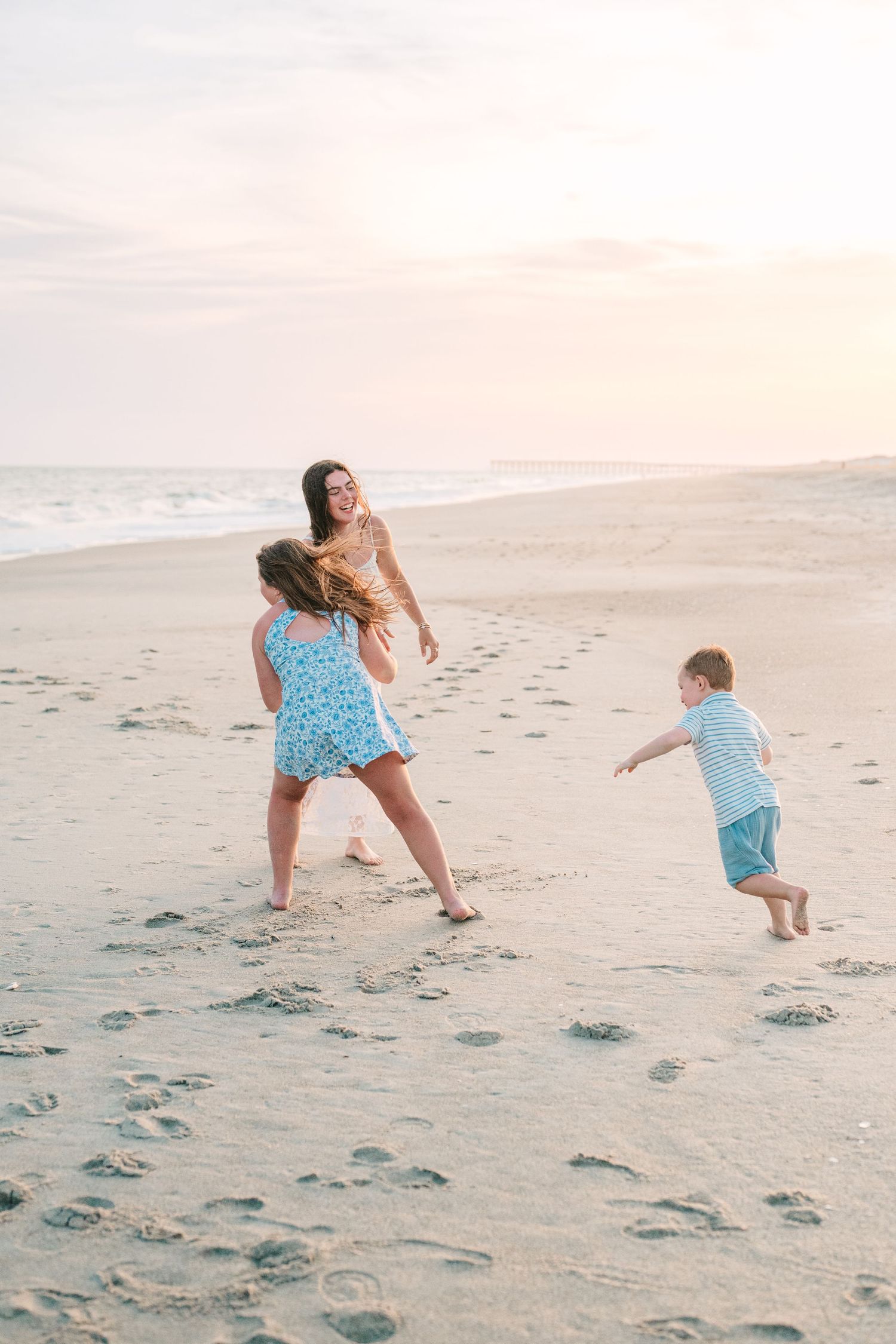 Playful moment captured of family running and playing on sandy beach.
