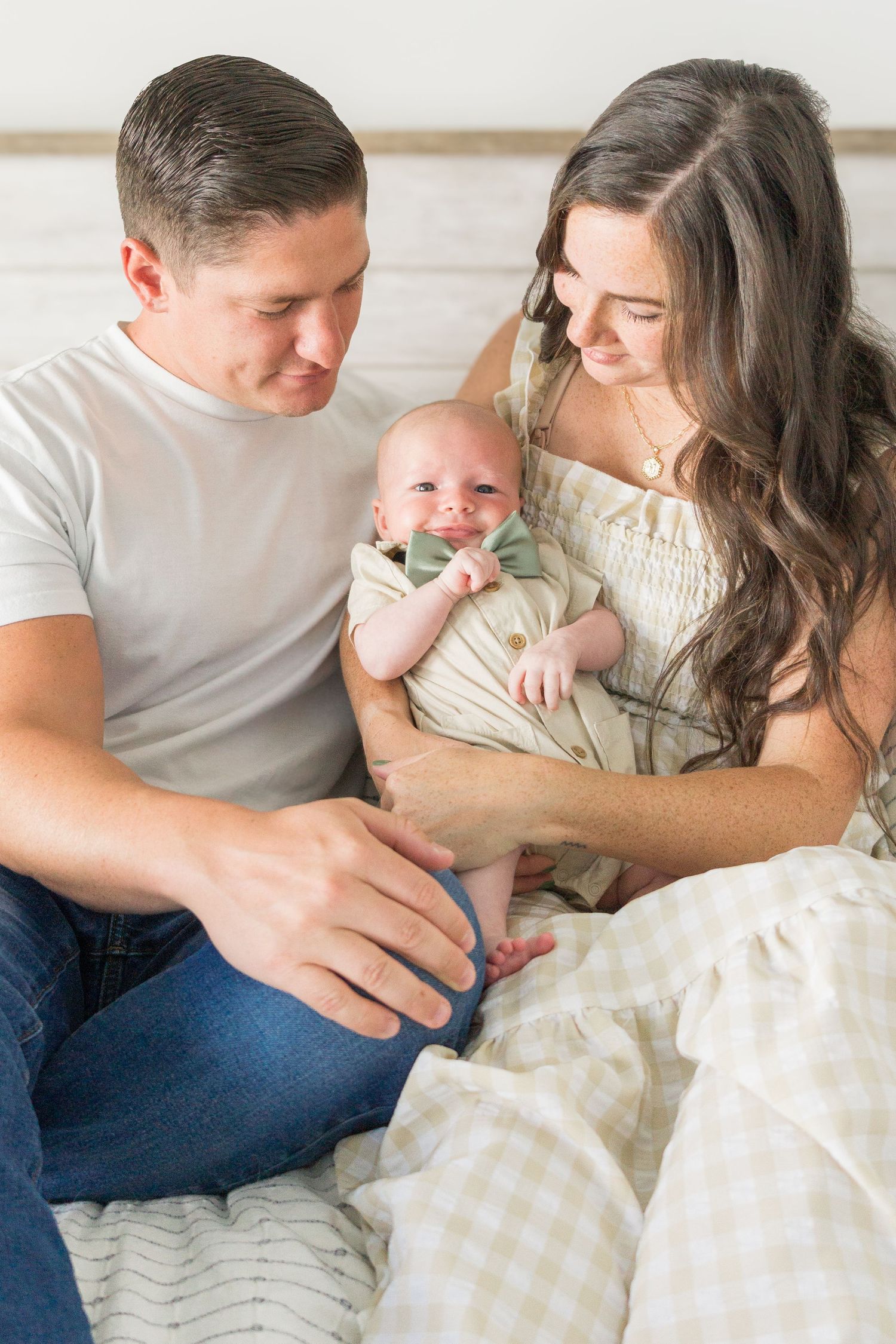 Parents sharing an intimate moment with their newborn baby on a cozy bed.