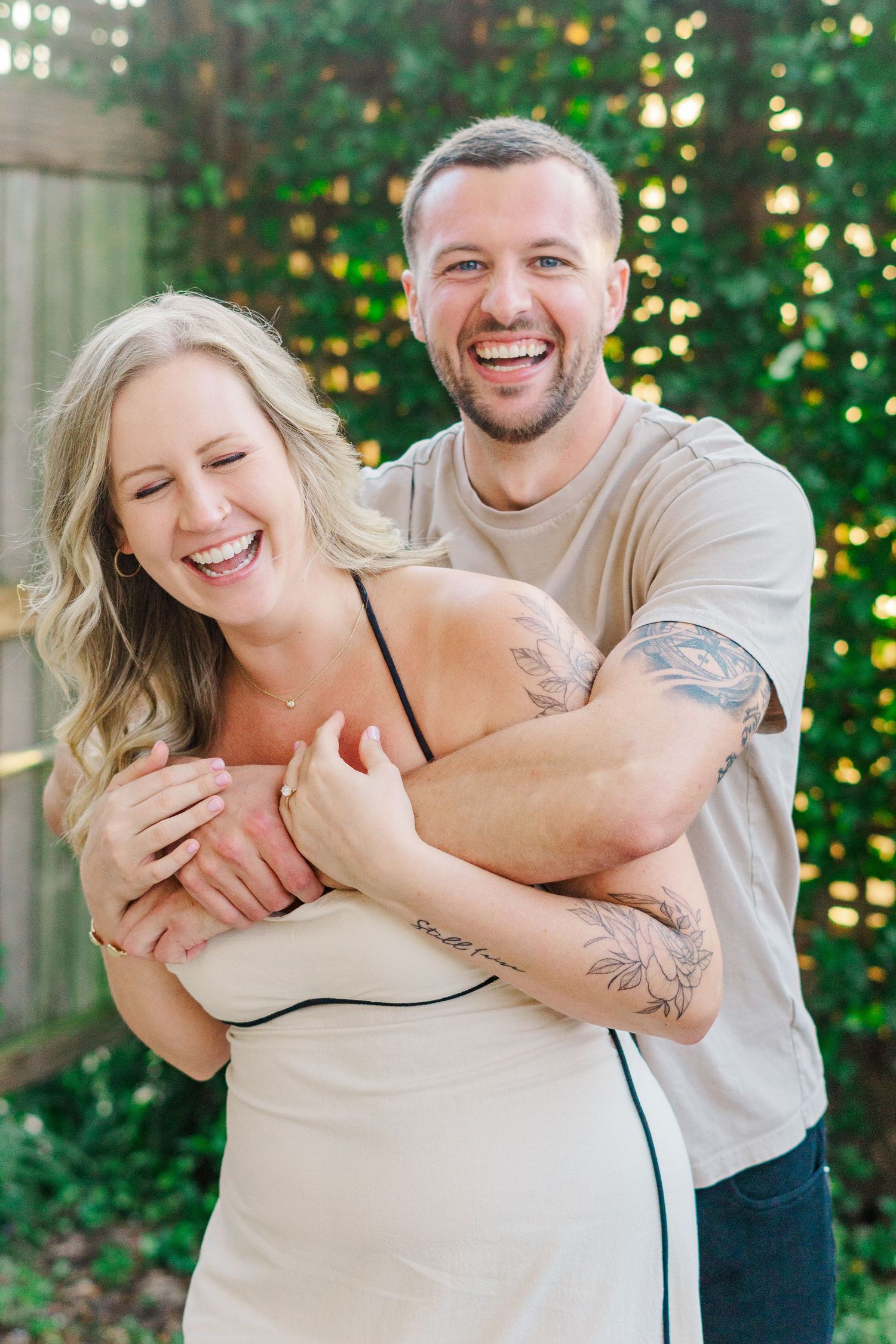 A playful embrace captured in a natural outdoor setting with greenery.