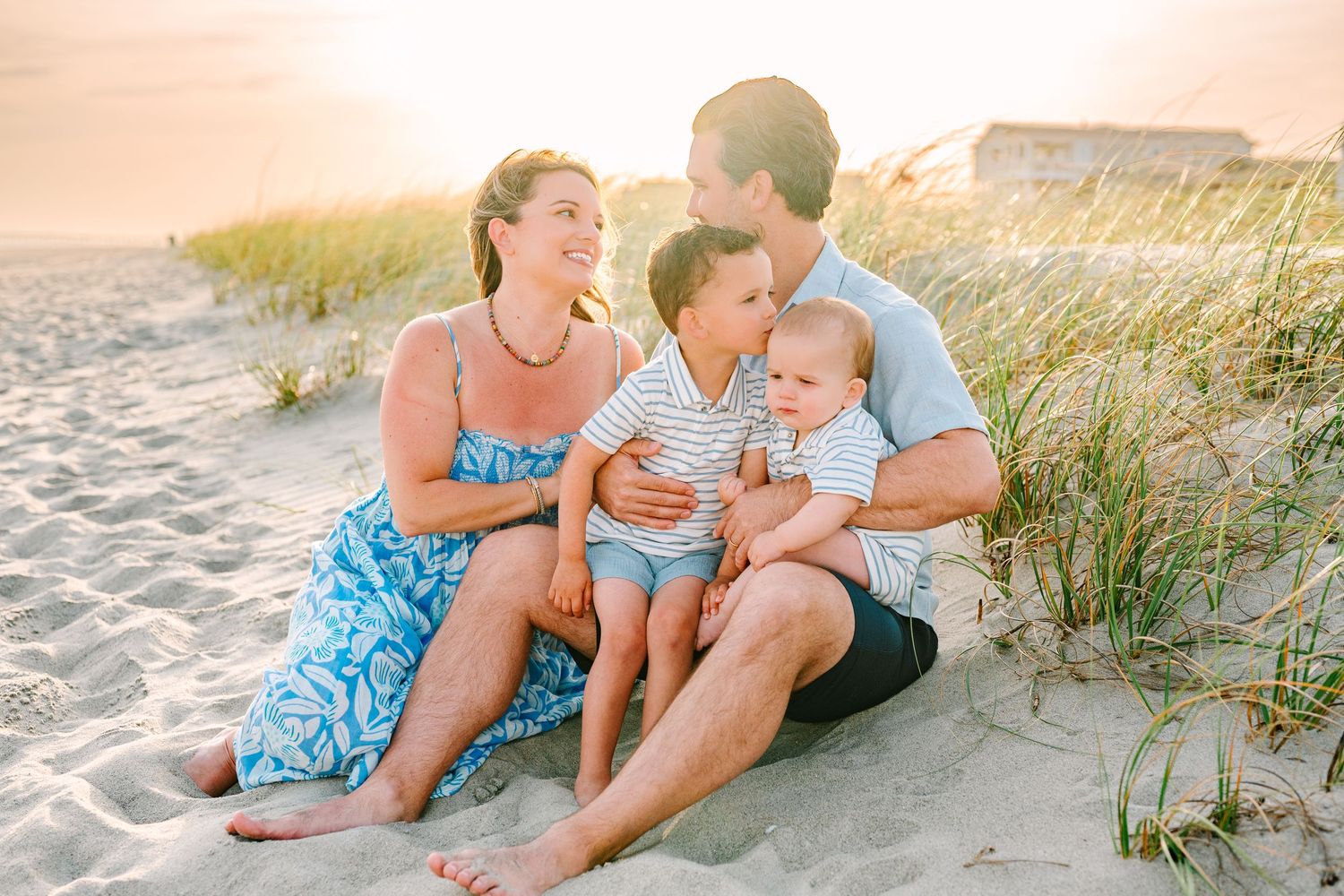 A candid family moment captured on the beach dunes during golden hour.