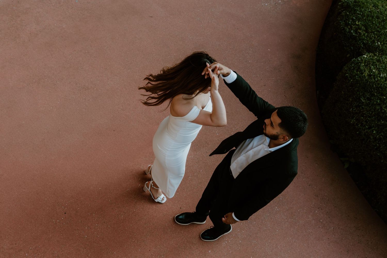 Dancing couple performs an elegant lift during a romantic outdoor dance sequence in low light conditions.