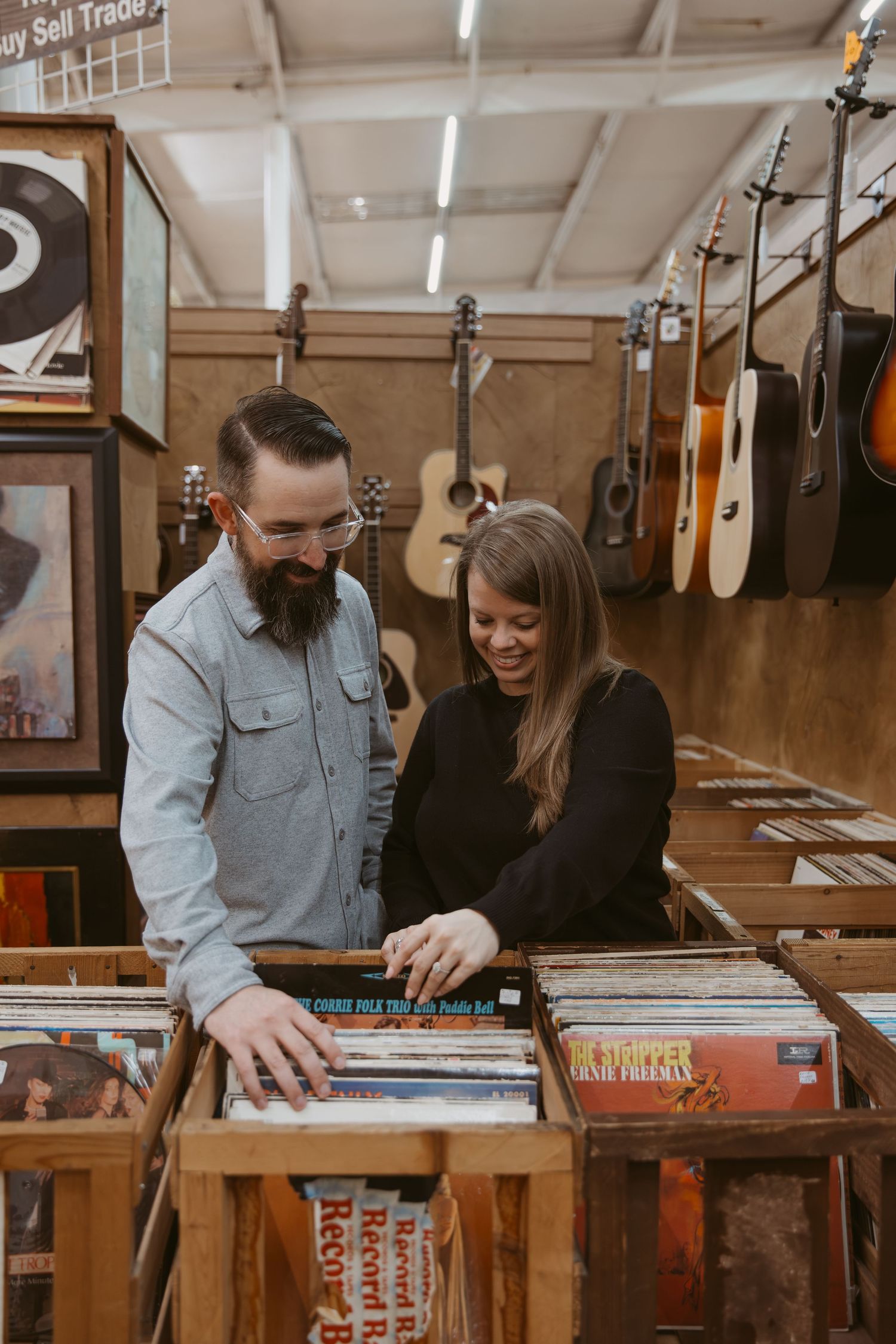 People looking through vinyl records together at a music shop with wooden display cases.