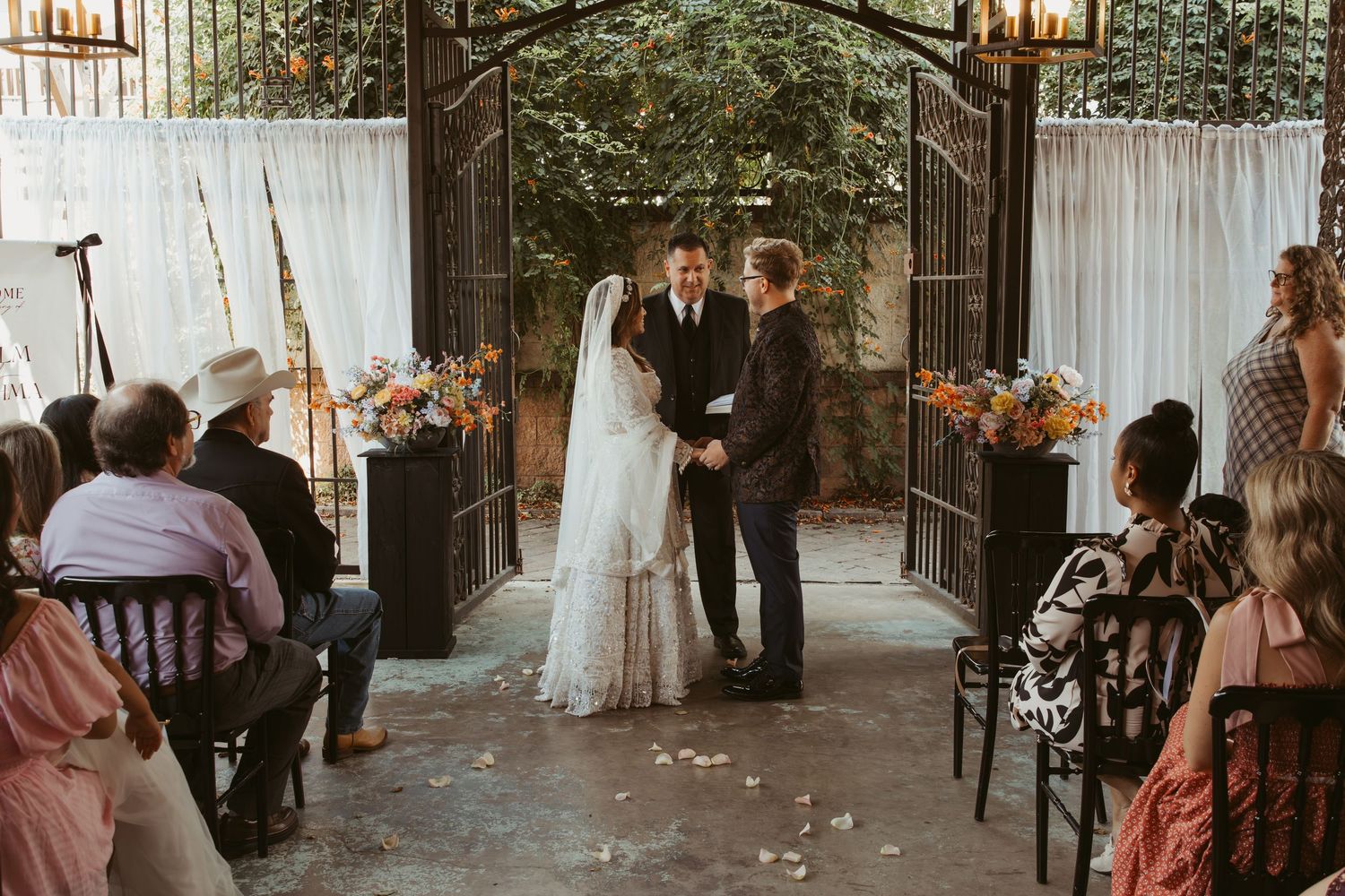 A panoramic view of an outdoor wedding reception venue with guests seated at long tables.