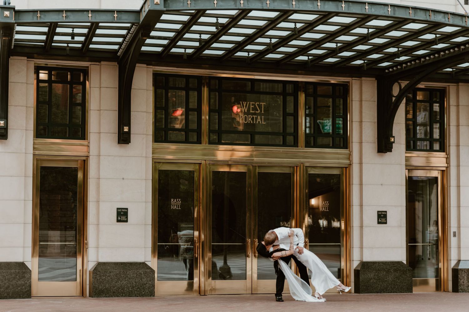 A modern storefront with a white exterior, black awning, and glass windows displaying retail merchandise. Engagement photographer DFW
