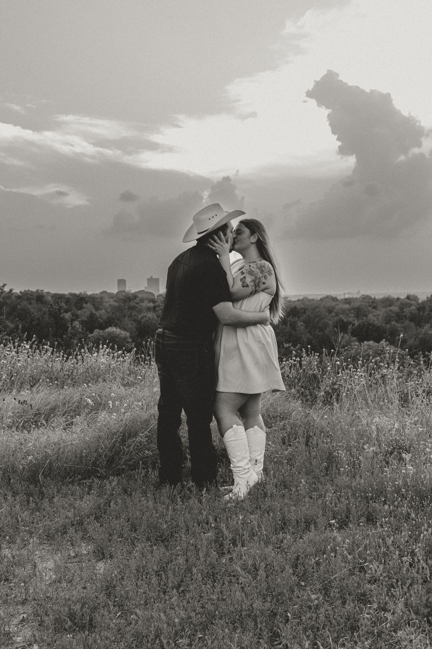 A romantic black and white photo series of a couple embracing in a wildflower meadow at sunset.