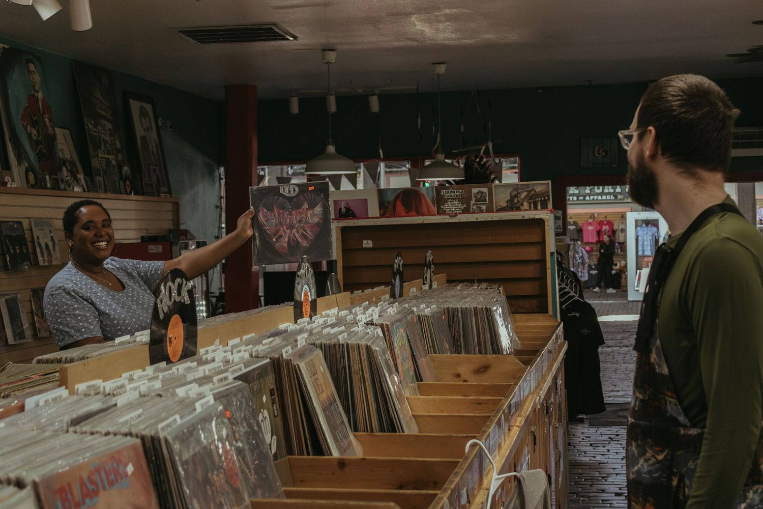 Two people browsing through vinyl records displayed in wooden crates at a music store.