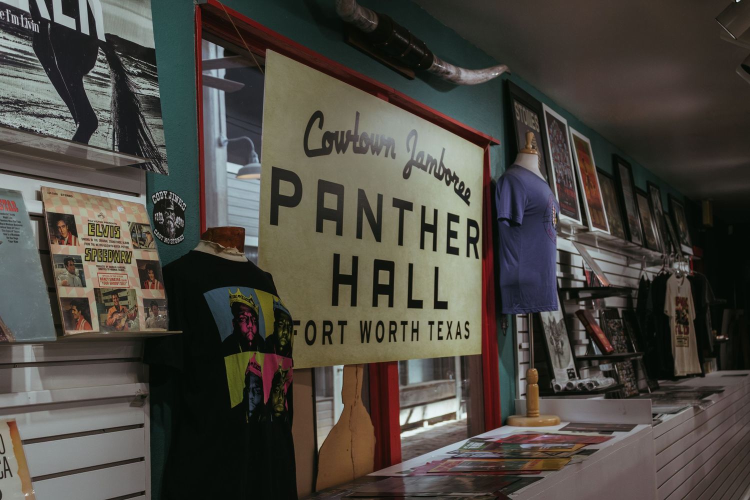 Vintage sign reading 'Panther Hall' from Fort Worth Texas displayed in a museum exhibit with memorabilia on the walls.