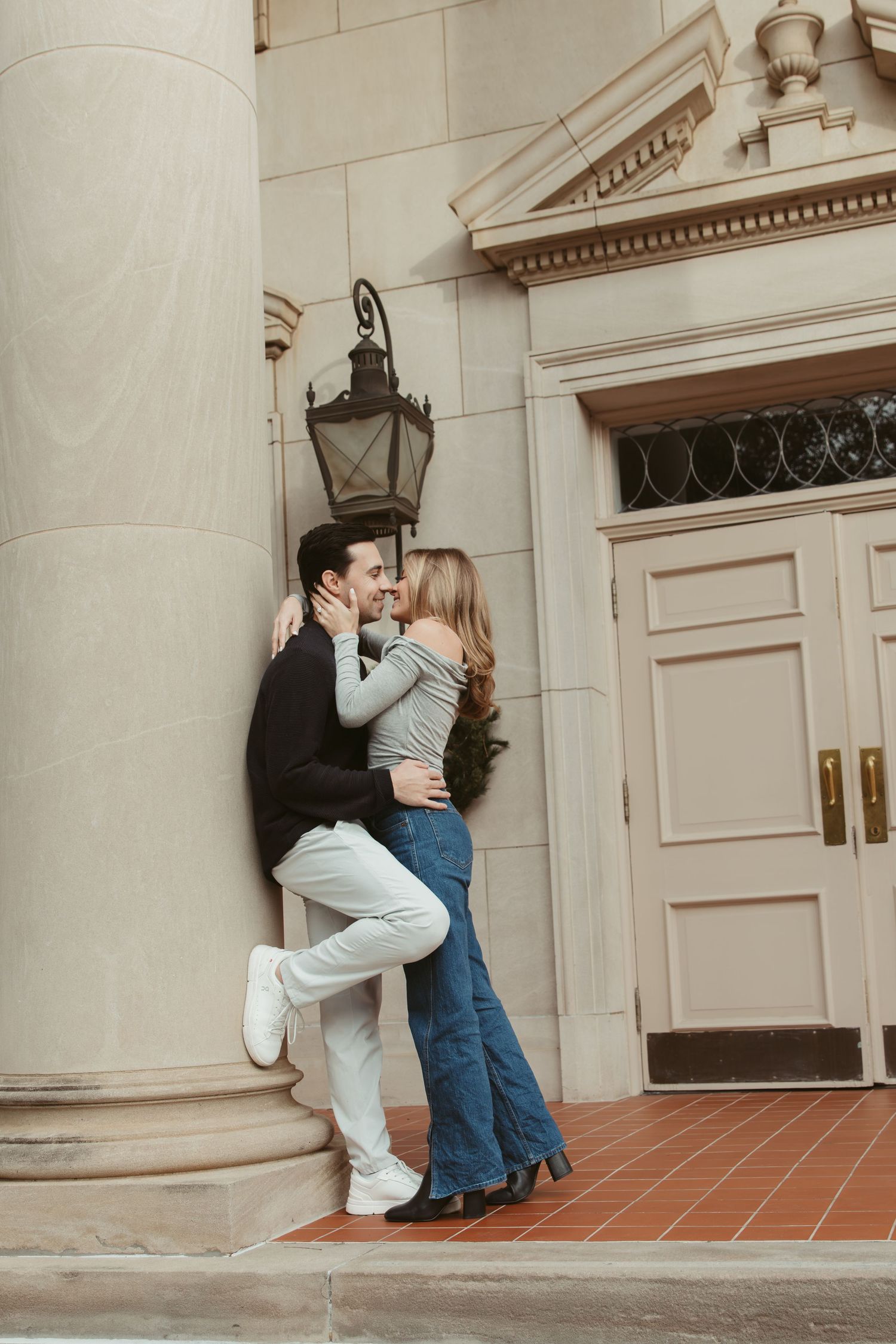 A romantic couple sharing intimate moments against a classic stone building entrance with columns. engagement photos Fort Worth