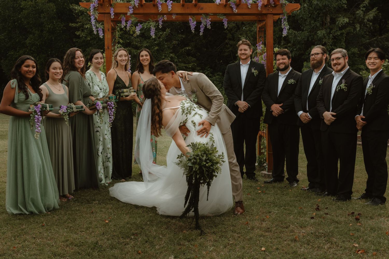 Wedding ceremony setup outdoors with wooden arch and gathered guests in formal attire.