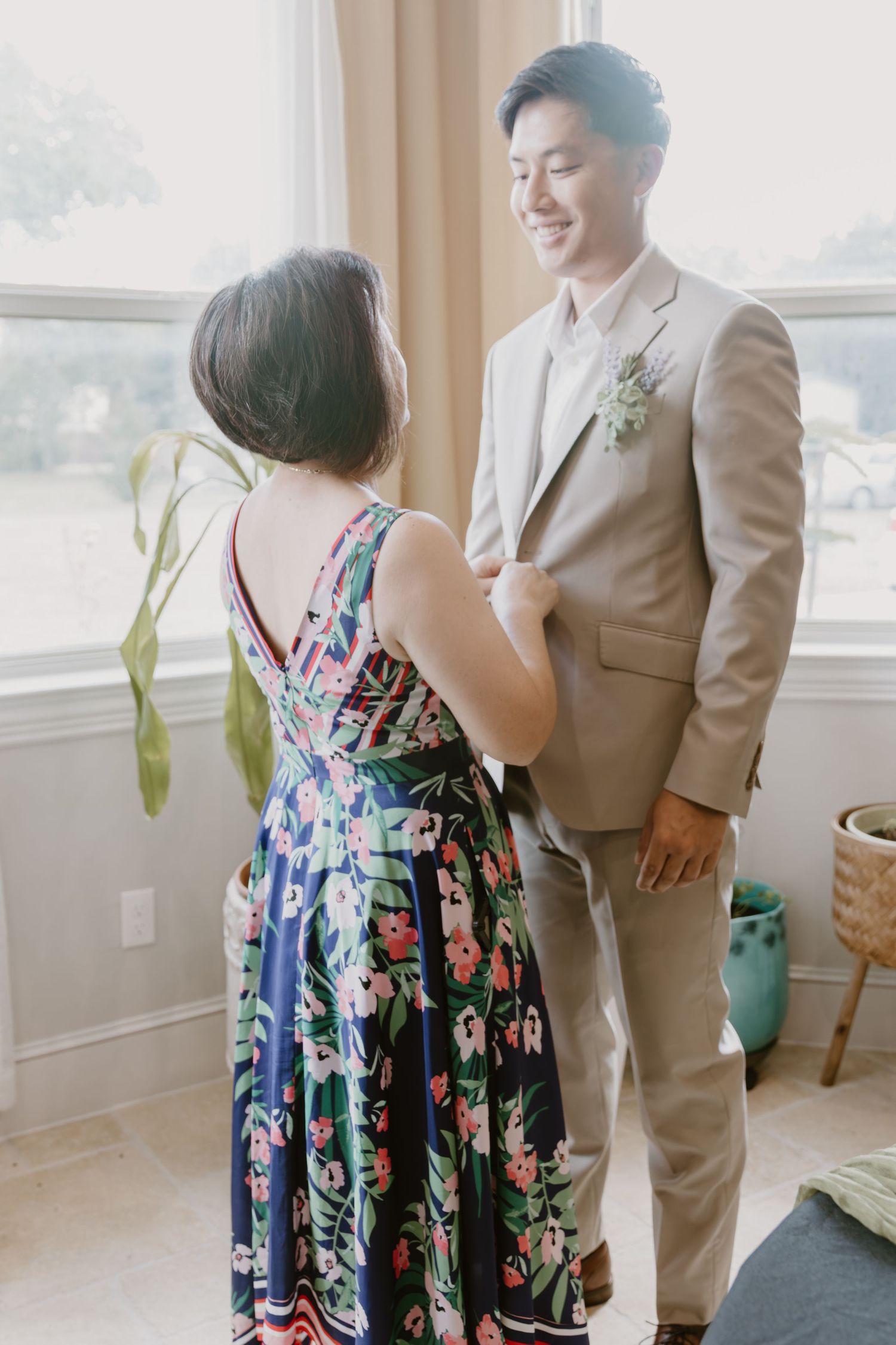 A couple sharing a tender moment by a bright window with floral decor.