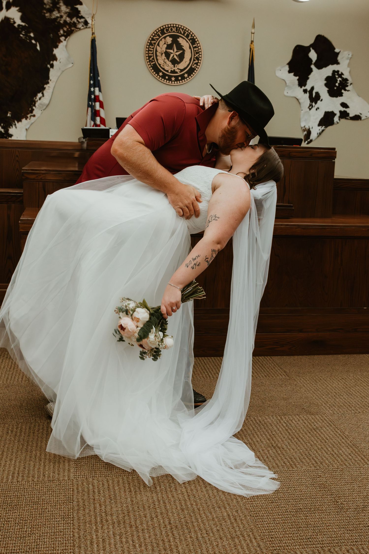 A dramatic wedding kiss pose in front of the Texas state seal during courthouse ceremony.