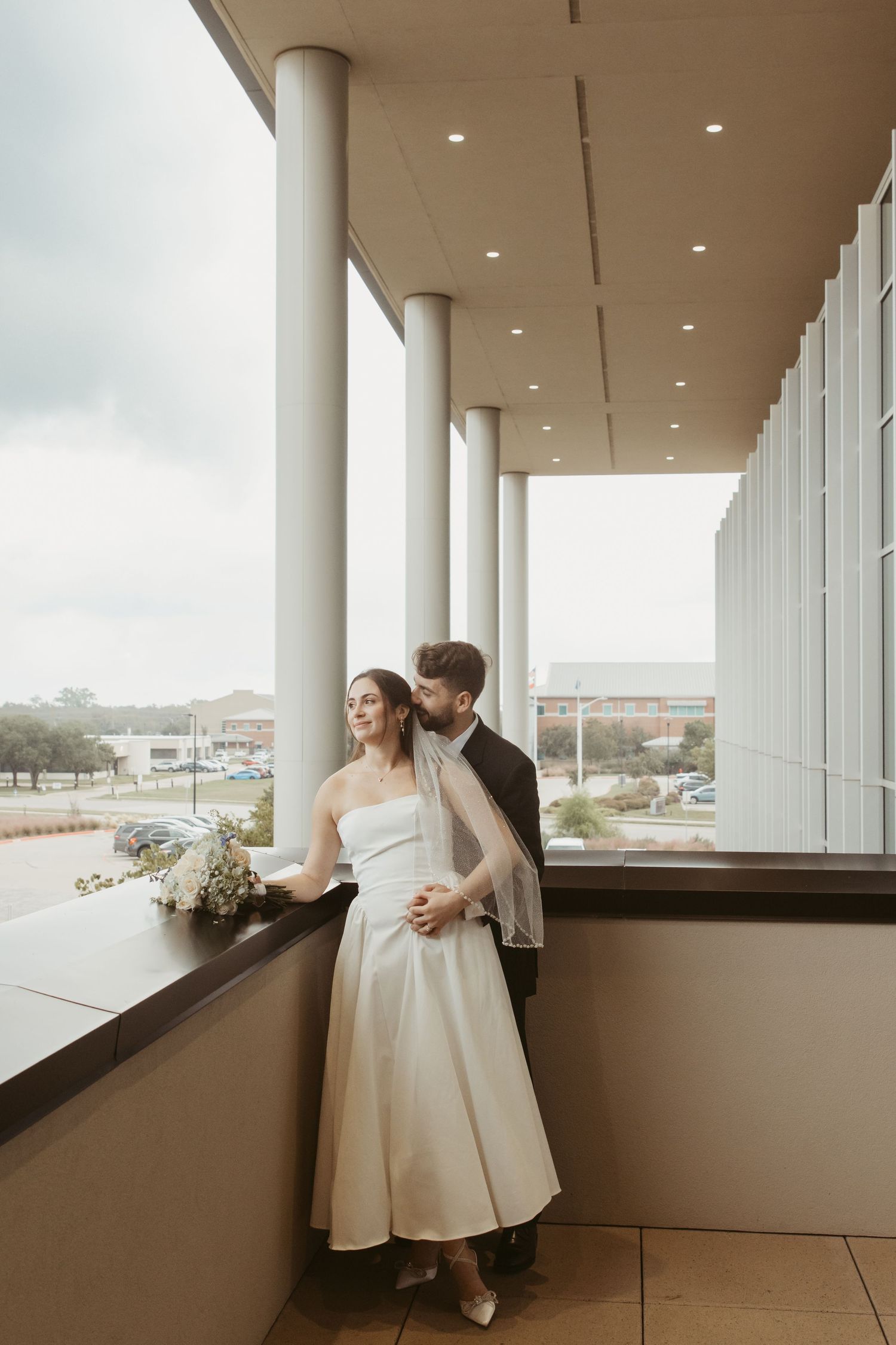 A wedding couple shares romantic moments along a covered balcony with scenic views. Wedding Photographer Fort Worth