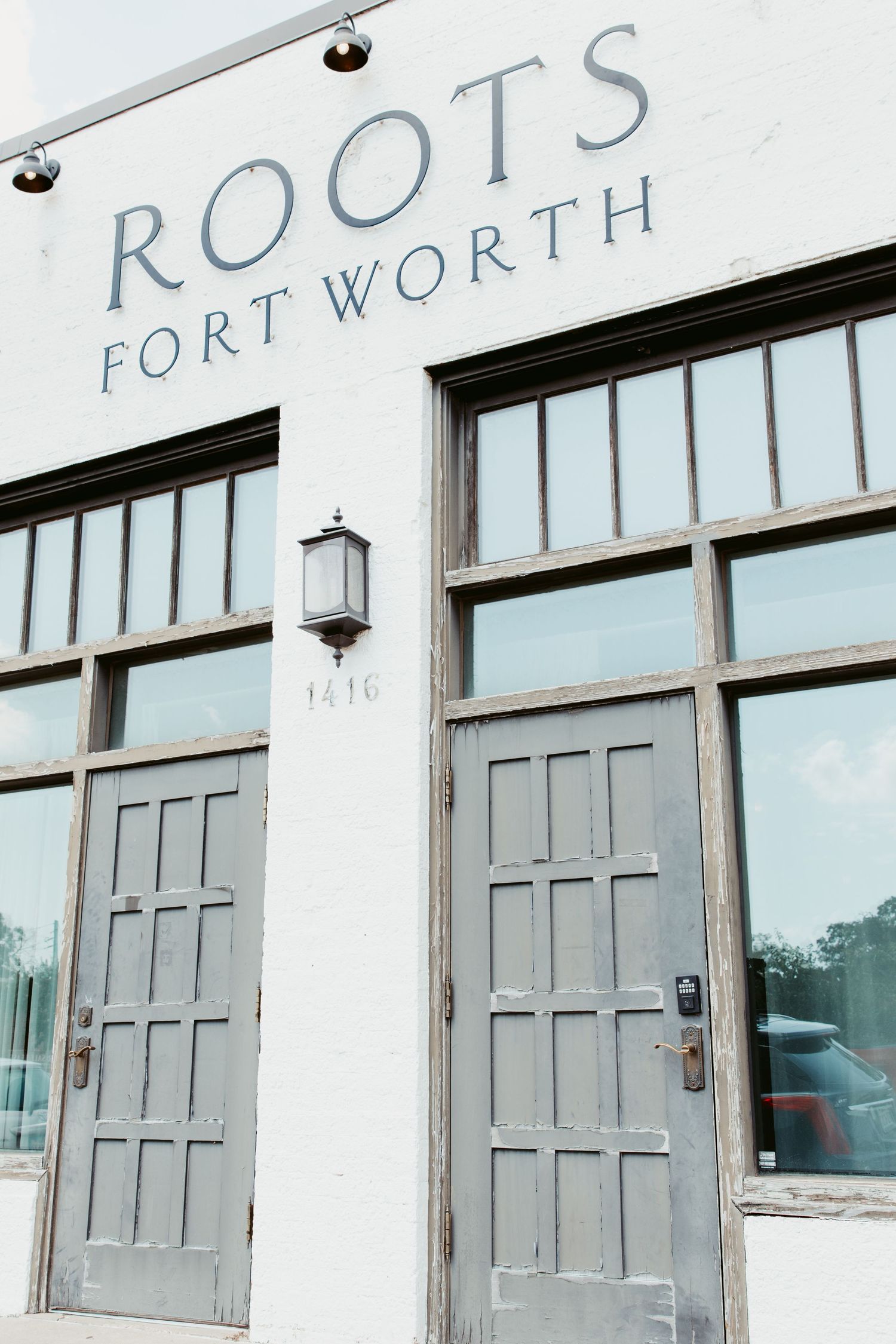 Exterior storefront with 'Roots Fort Worth' signage and grey paneled doors.