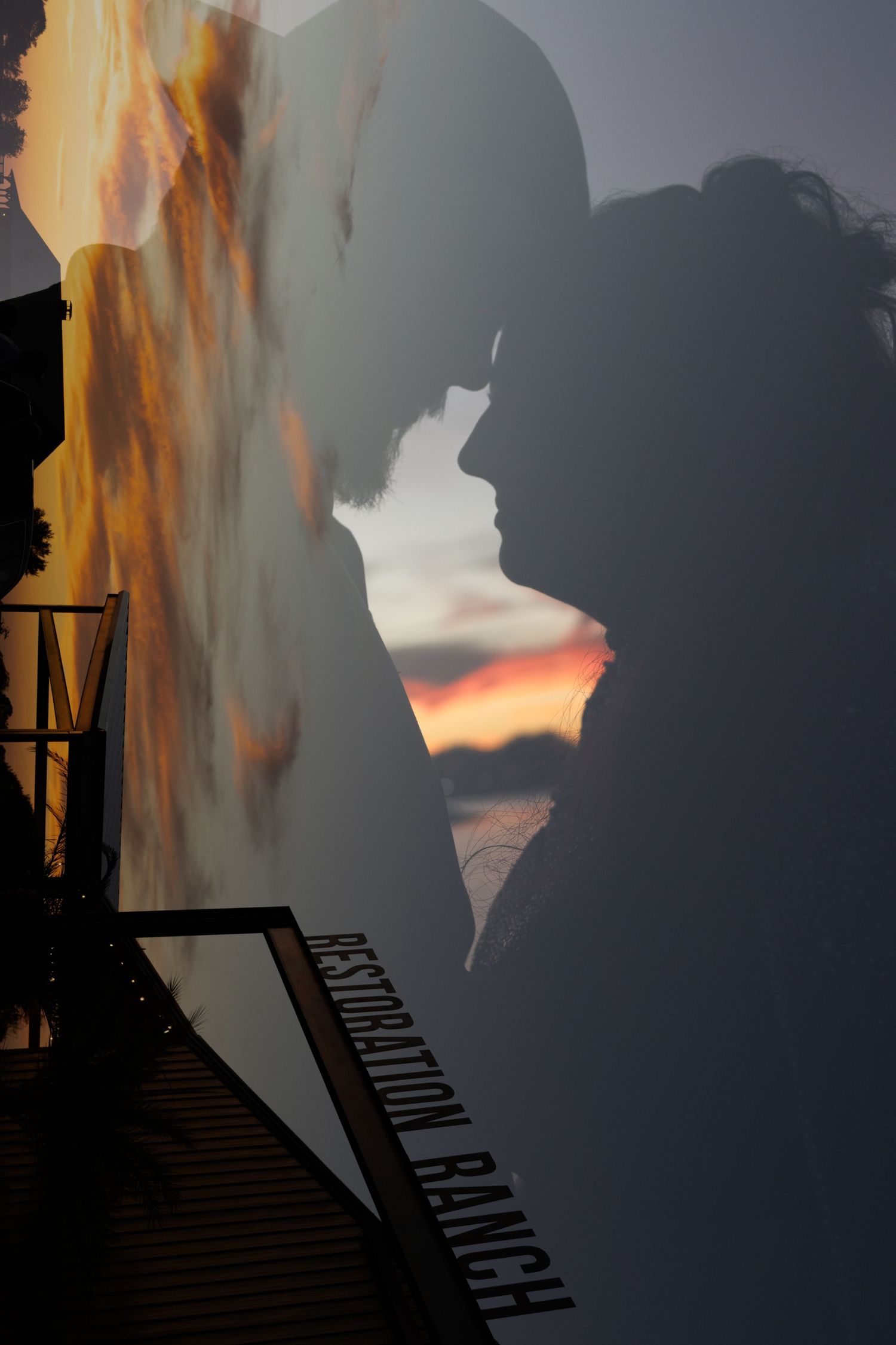 Dramatic sunset sky with silhouettes of structures against vibrant orange and gray clouds. Wedding photographer DFW