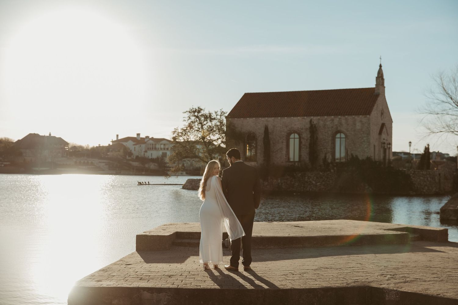 Panoramic view of a couple embracing near a stone church during a dramatic sunset.