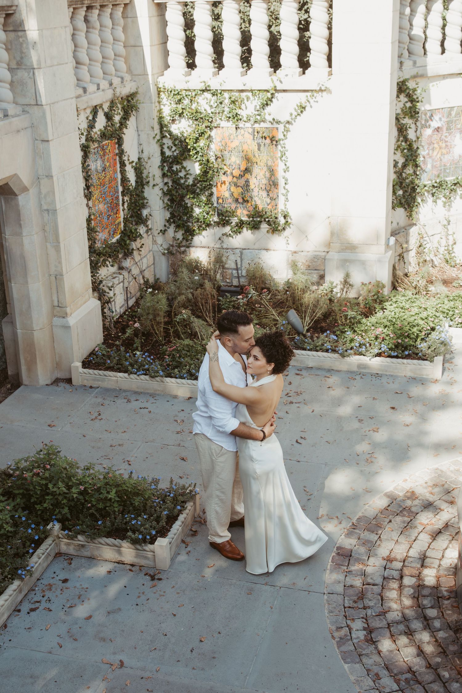 A sequence of wedding photos showing a couple dancing and embracing near a stone balustrade and brick pathway.