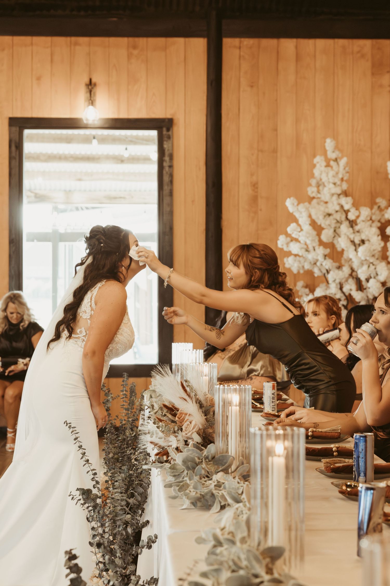 Wedding reception setup in a rustic venue with white floral arrangements and candlelight decorations. Wedding photographer DFW