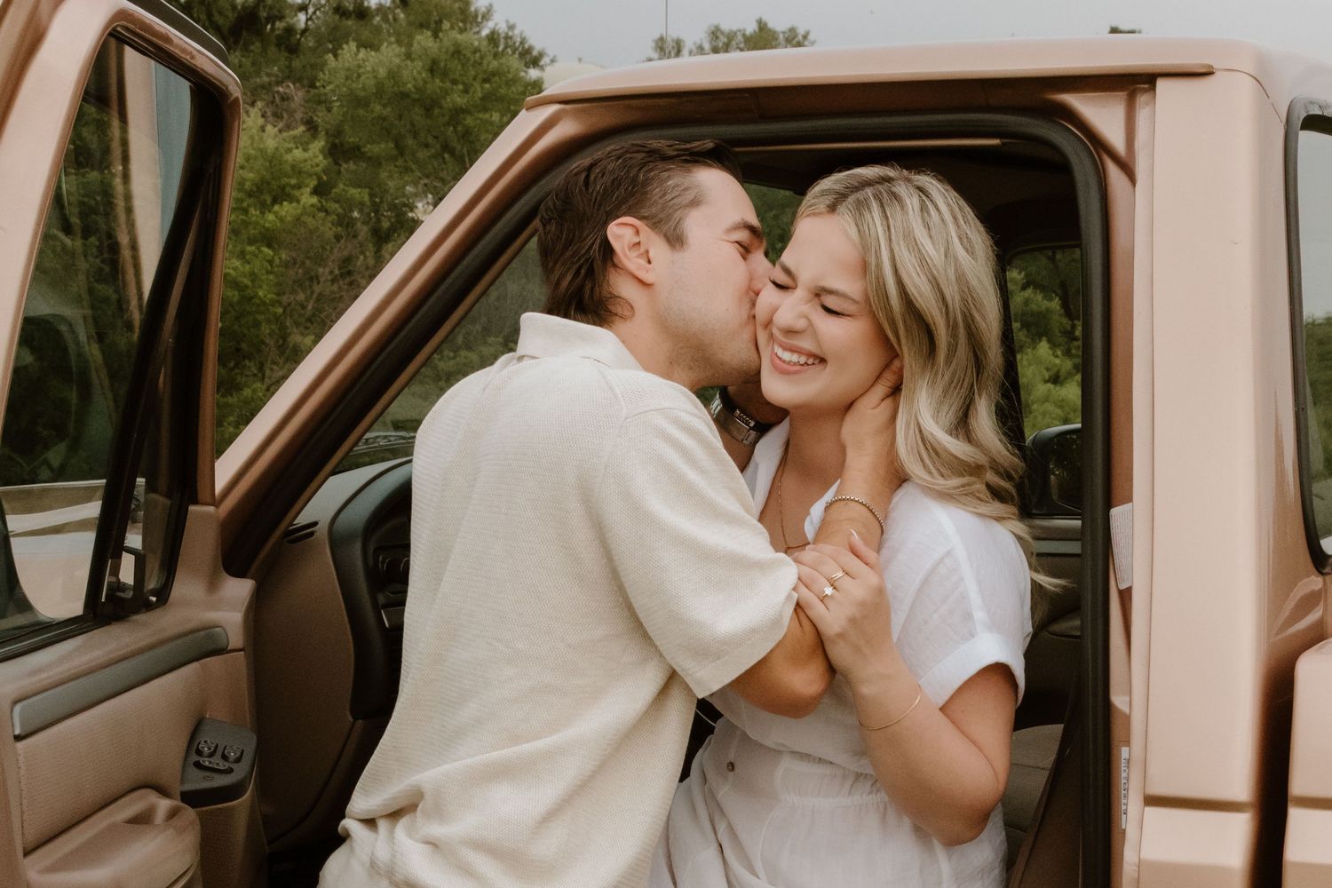 A romantic moment shared between two people in front of a vintage truck in warm sunlight.