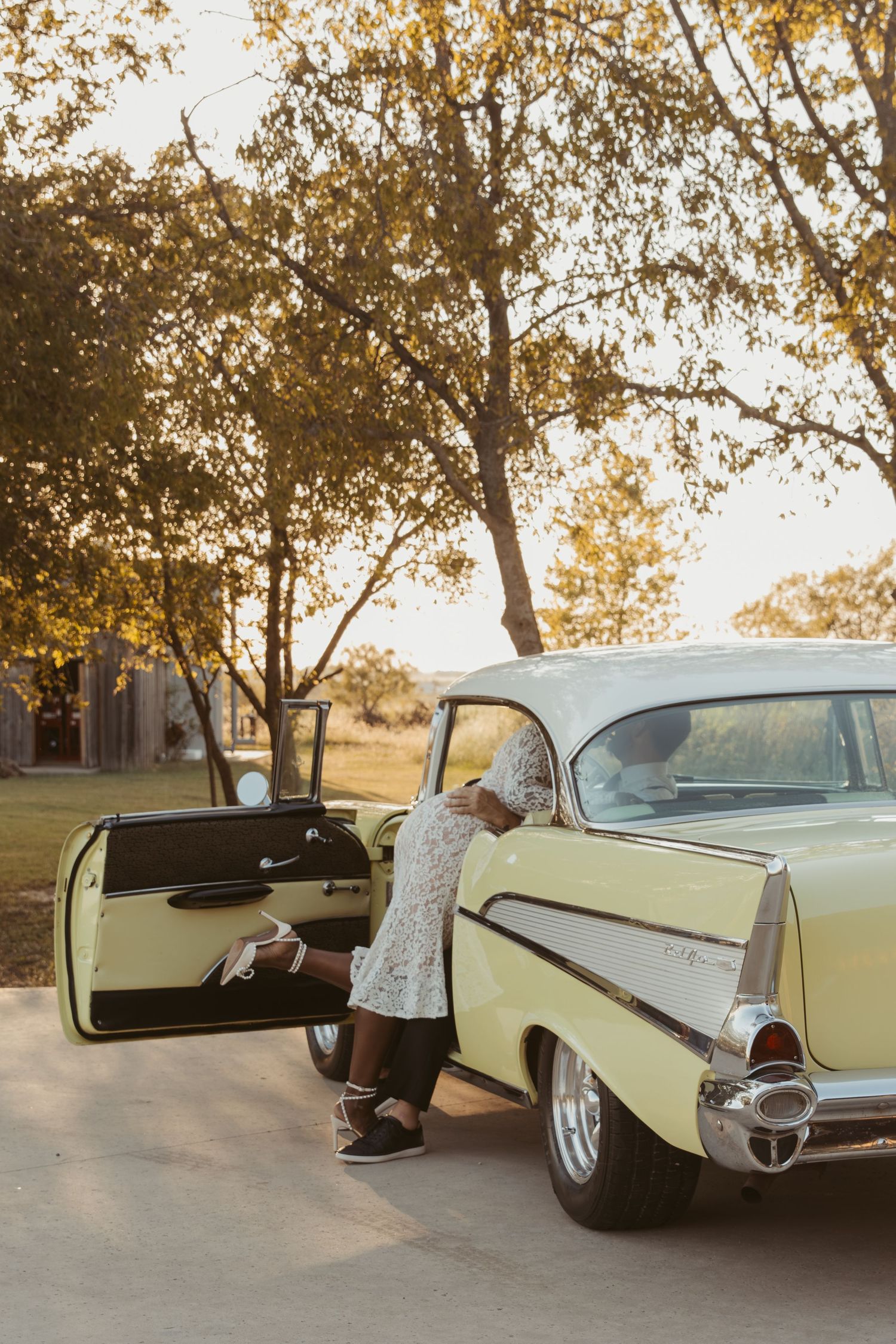 A classic cream-colored vintage car is shown in a series of connected photos at sunset with trees in the background.