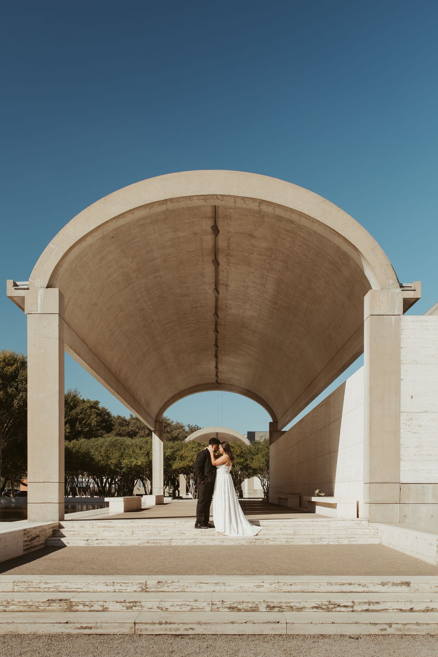 Architectural series showing minimalist concrete arches and columns of a modern structure against a blue sky. Wedding Photographer DFW