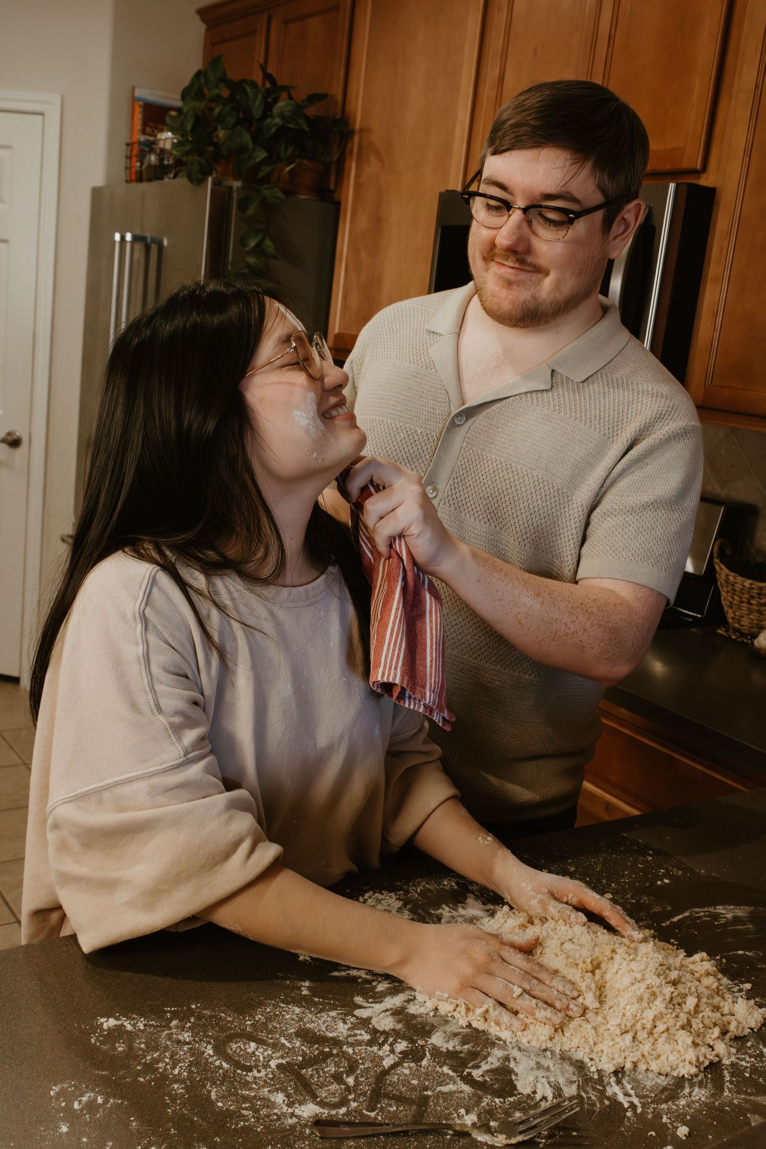 A couple having fun while making homemade pasta dough in their kitchen.