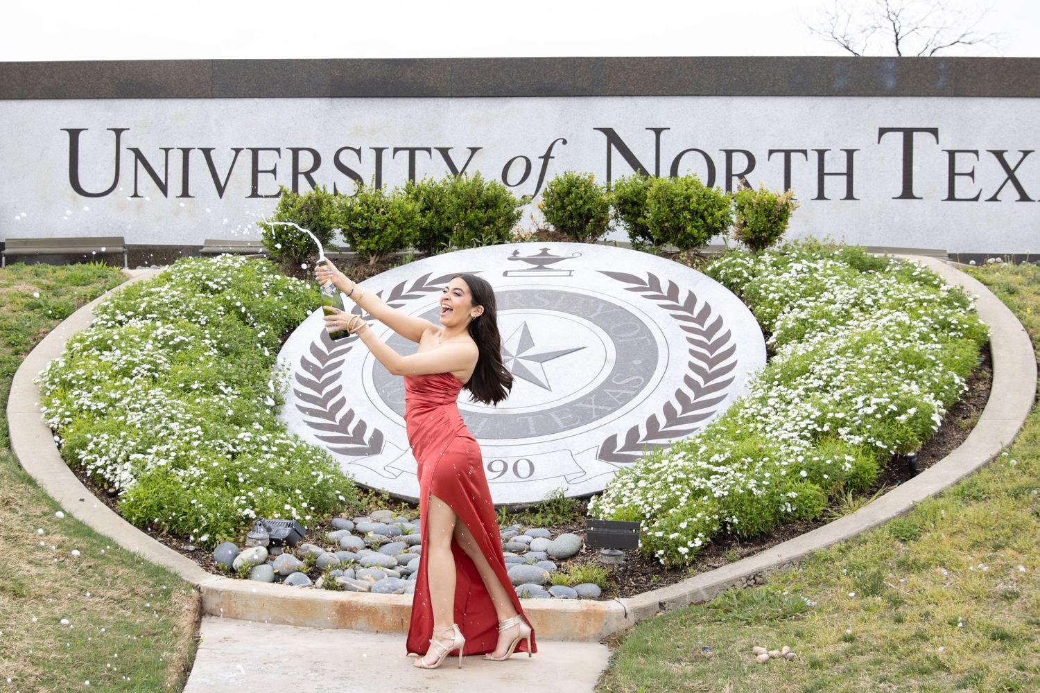 A graduation celebration pose at the University of North Texas seal garden.