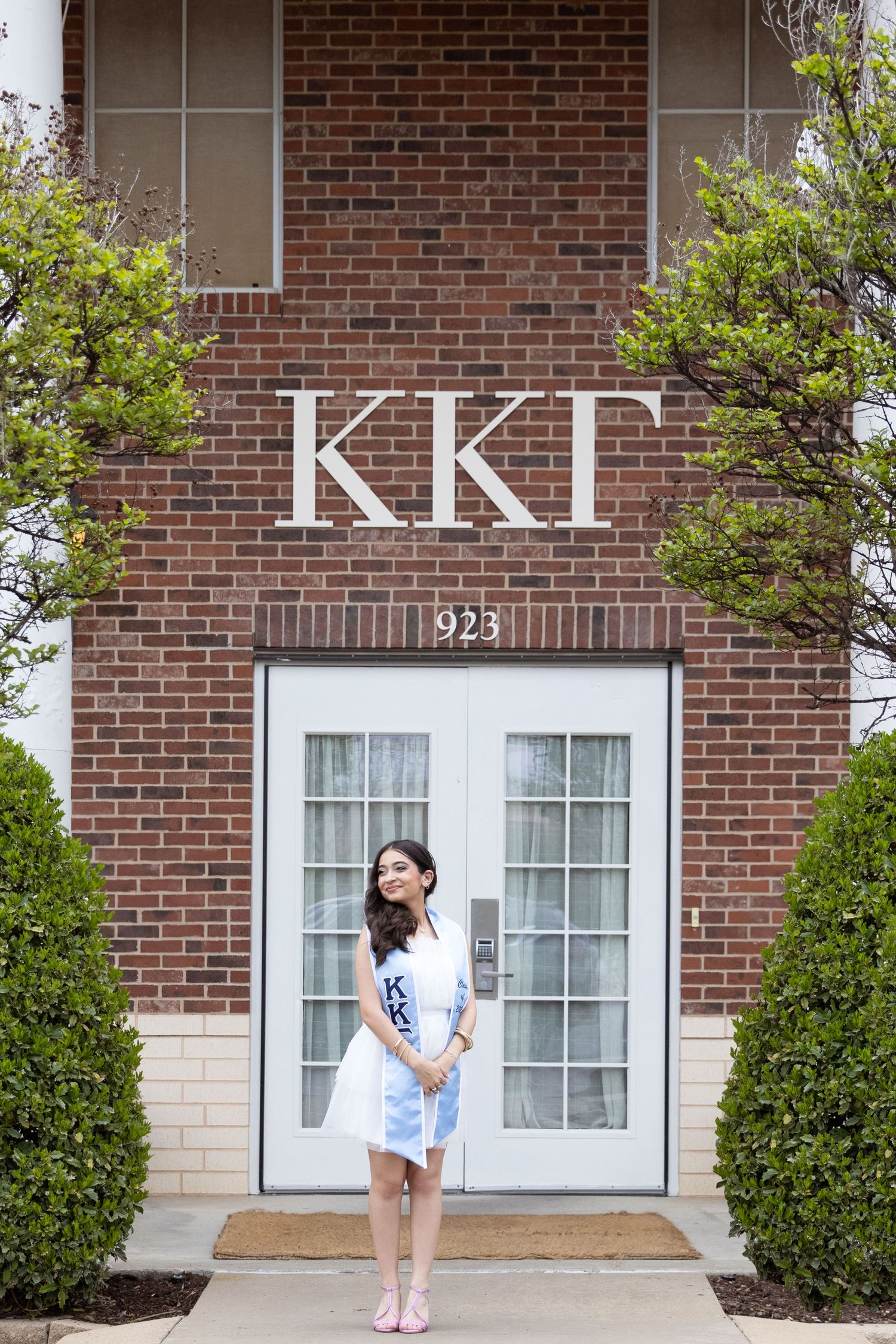 Kappa Kappa Gamma Sorority House. A brick building entrance with 'KKG' letters and '923' address number displayed above double glass doors.