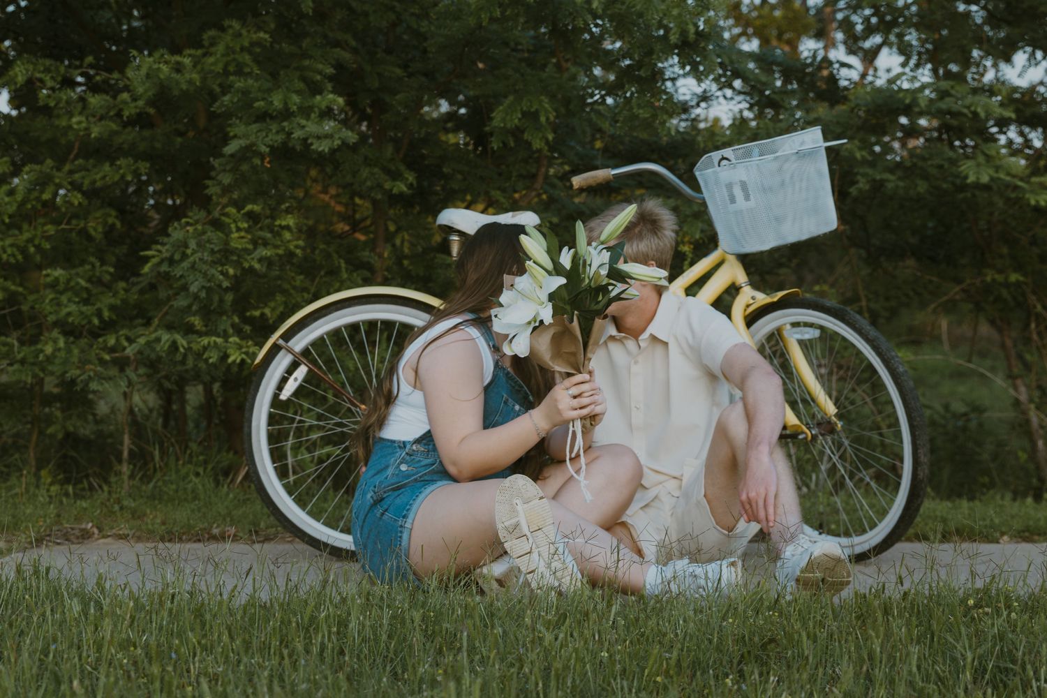 A romantic vintage-style picnic on grass with a white cruiser bicycle in the background during golden hour.