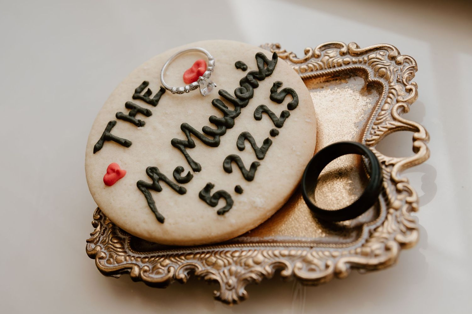 Wedding date and ring displayed on decorative ceramic plate with heart details.
