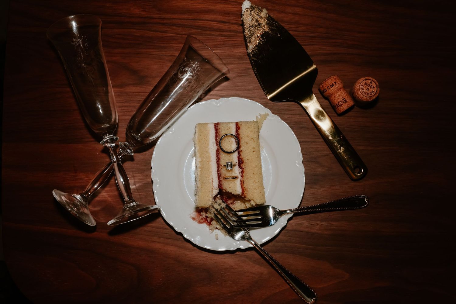 Smores dessert on white plate with champagne glasses and bottle on dark wooden table.