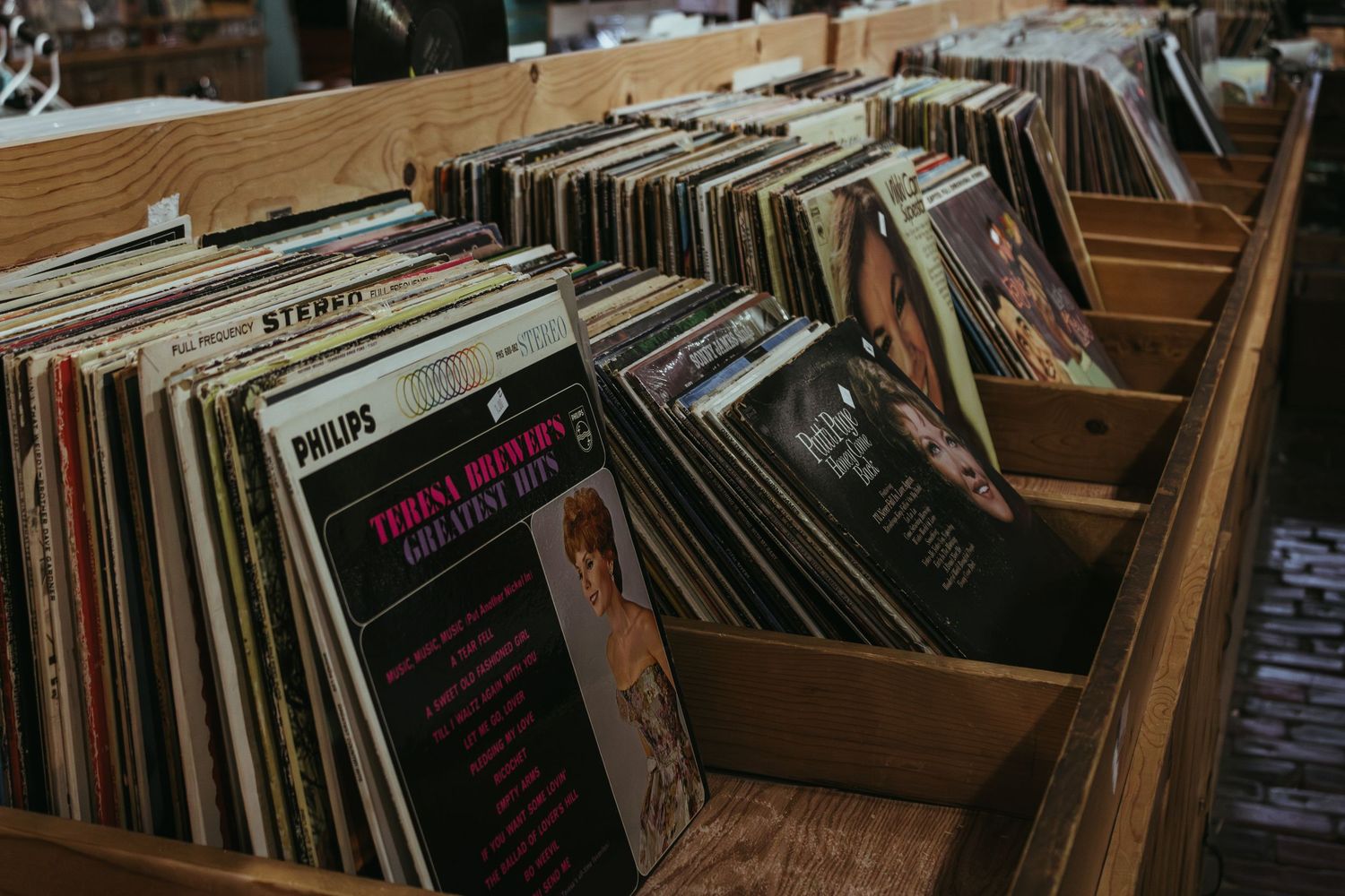 Vinyl records organized in wooden crates at a record store or music collection display.