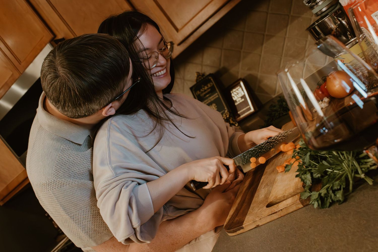 A joyful couple laughing while cooking together in their kitchen.