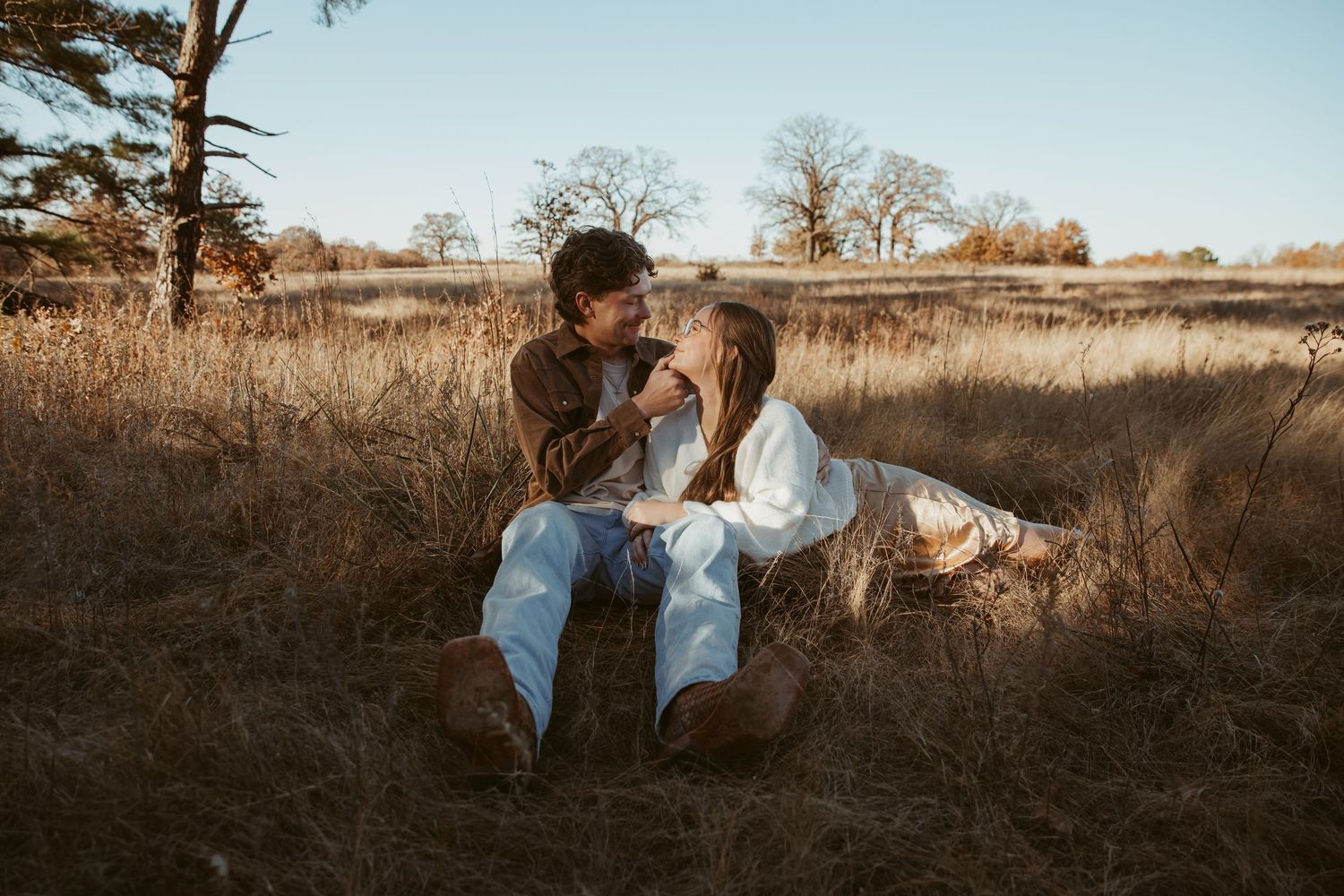 A romantic couple embraces in a golden field during sunset creating a warm and intimate outdoor portrait. engagement photos DFW