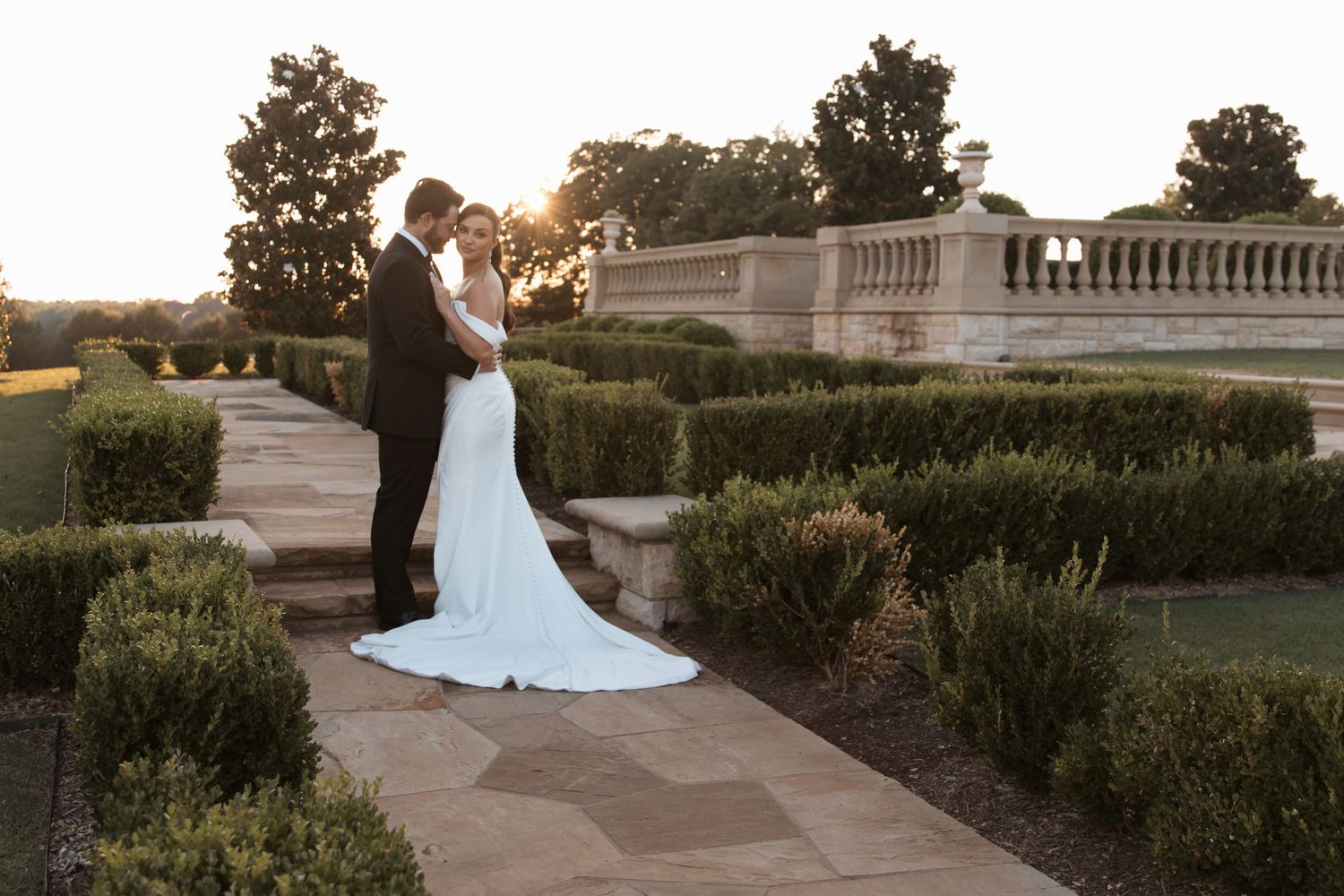 Elegant bridal portraits at sunset on a grand estate with manicured gardens and stone balustrades.