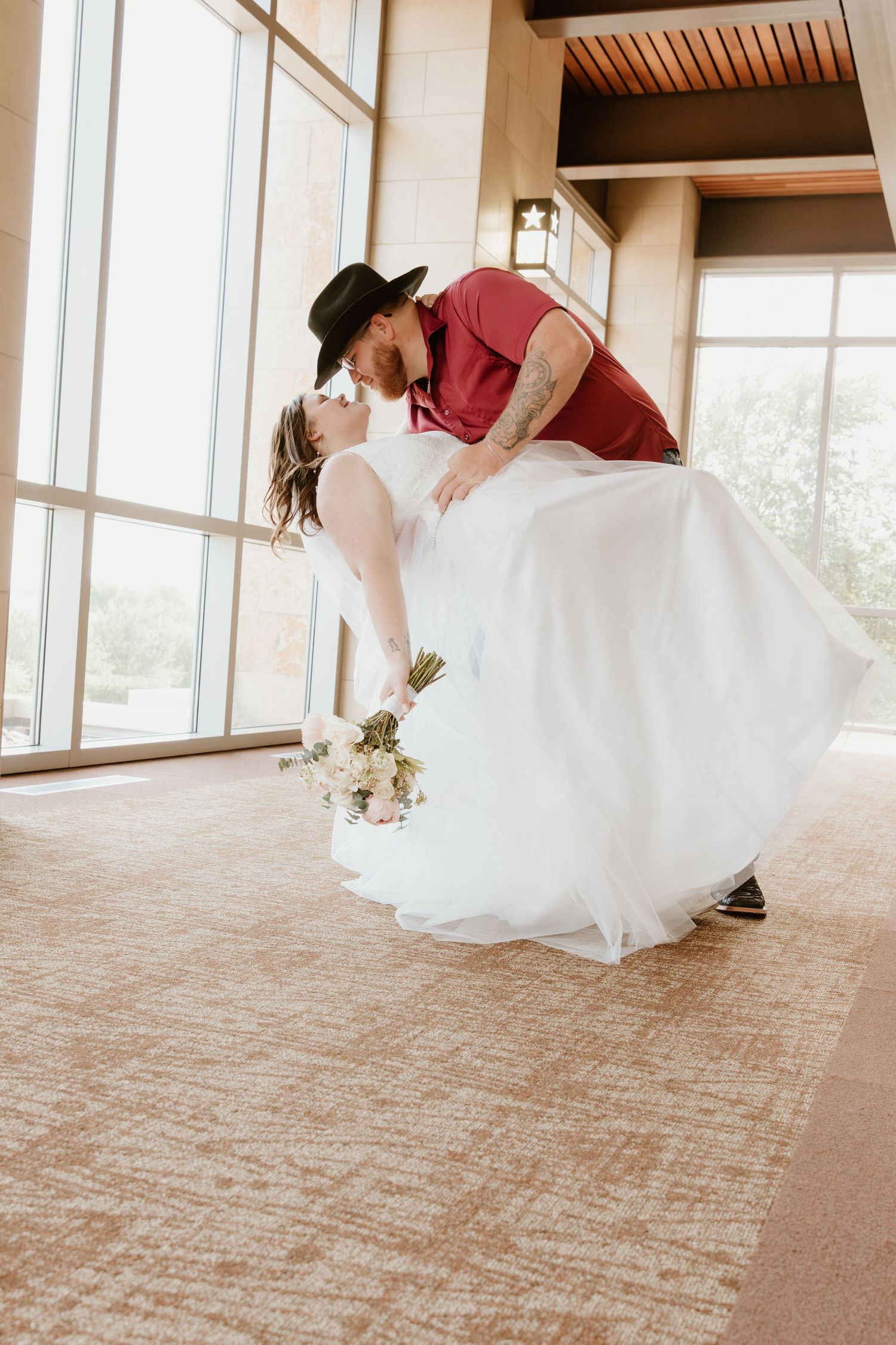 Romantic dance dip pose on carpeted floor with flowing white wedding dress.