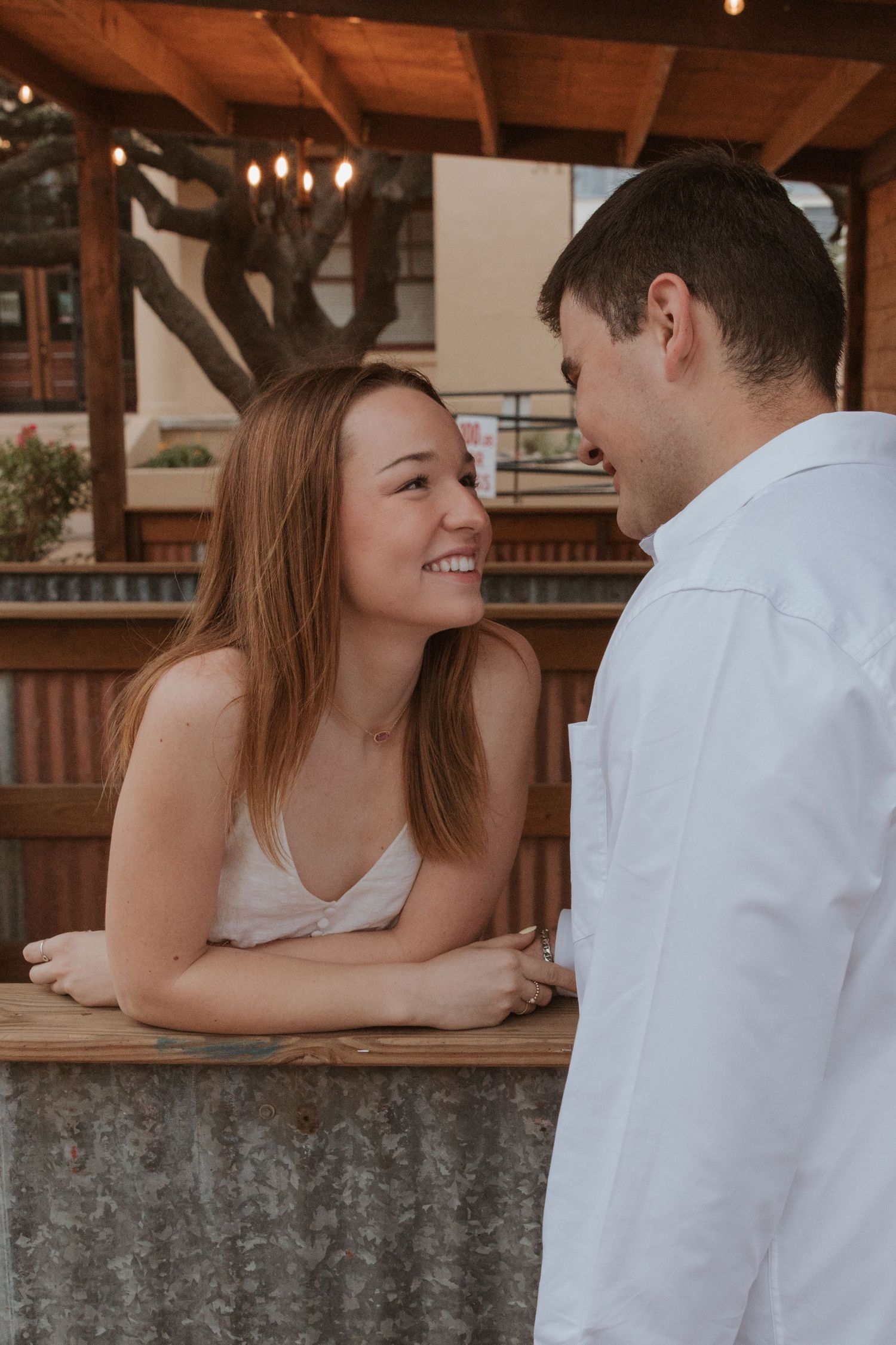 Candid moment between a couple sharing a laugh while leaning on a rustic wood bar counter indoors.