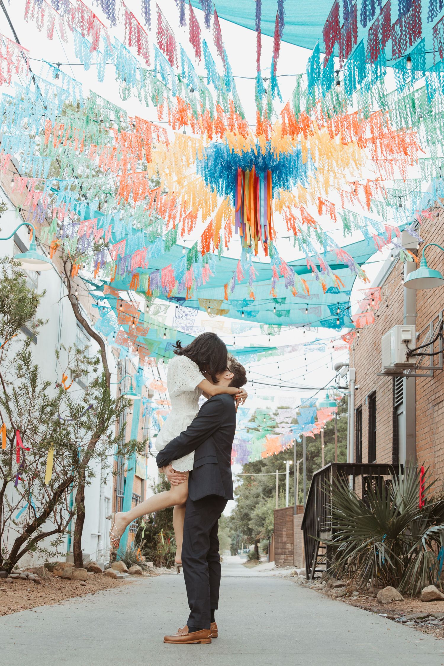 A series of photos showing a couple dancing under colorful streamers decorating an urban alleyway.