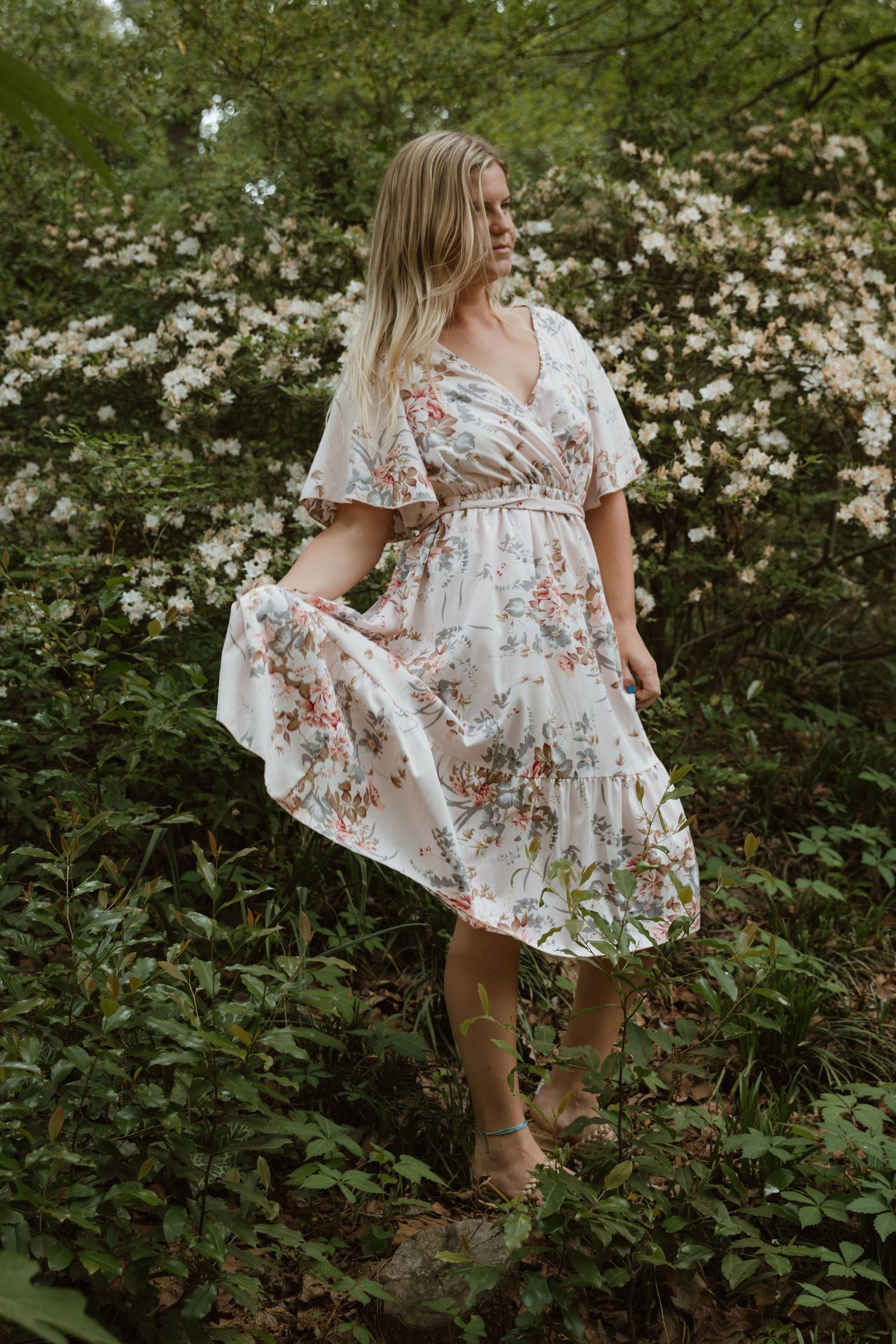 A flowing white floral dress twirls gracefully among blooming spring flowers and greenery.