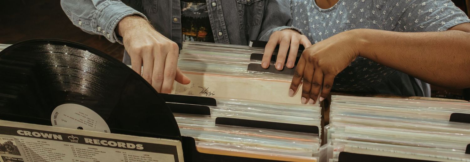 Two people looking through vinyl records at a table, sorting and browsing through the collection together.